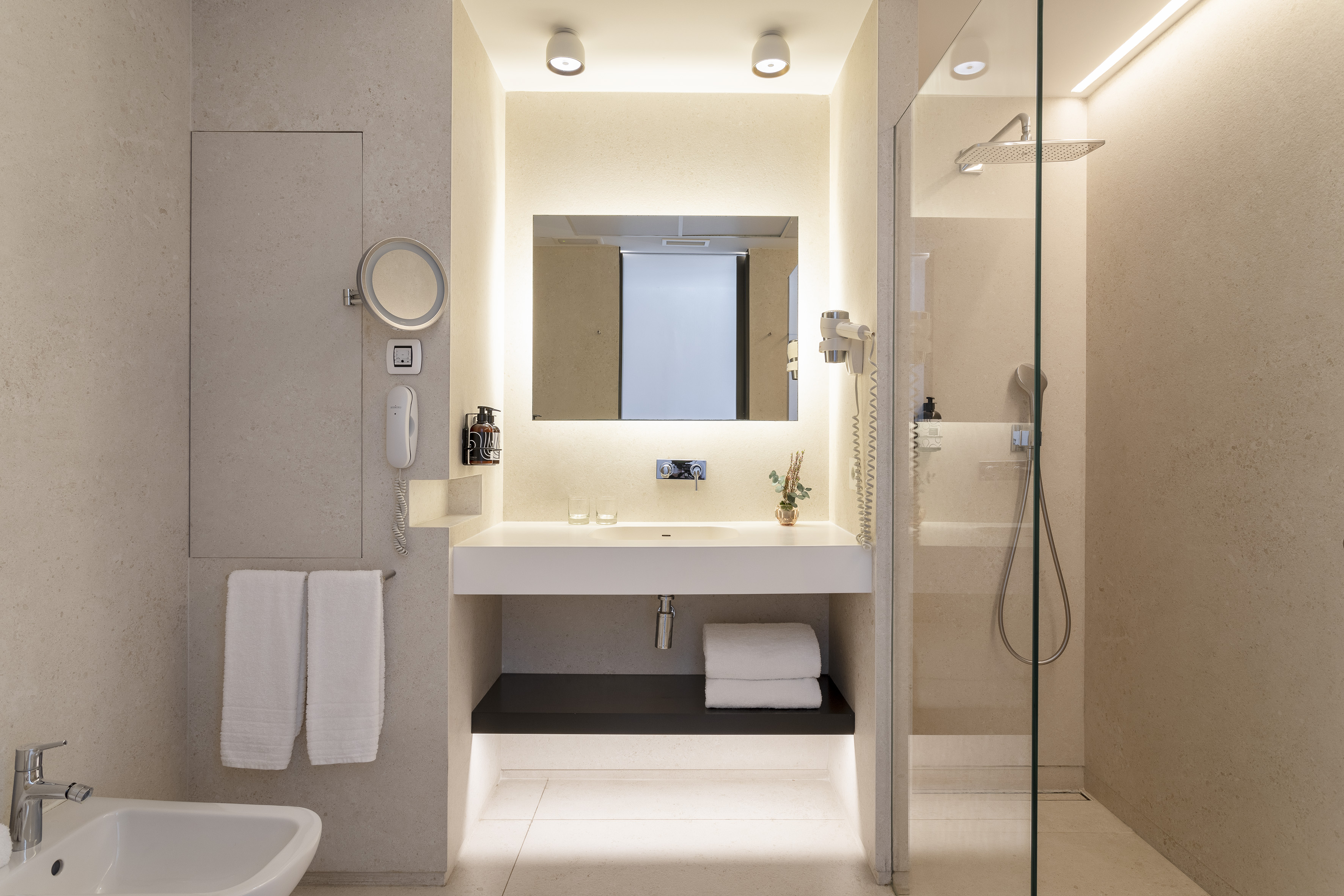 Modern neutral bathroom with backlit mirror, vanity, and walk-in shower.
