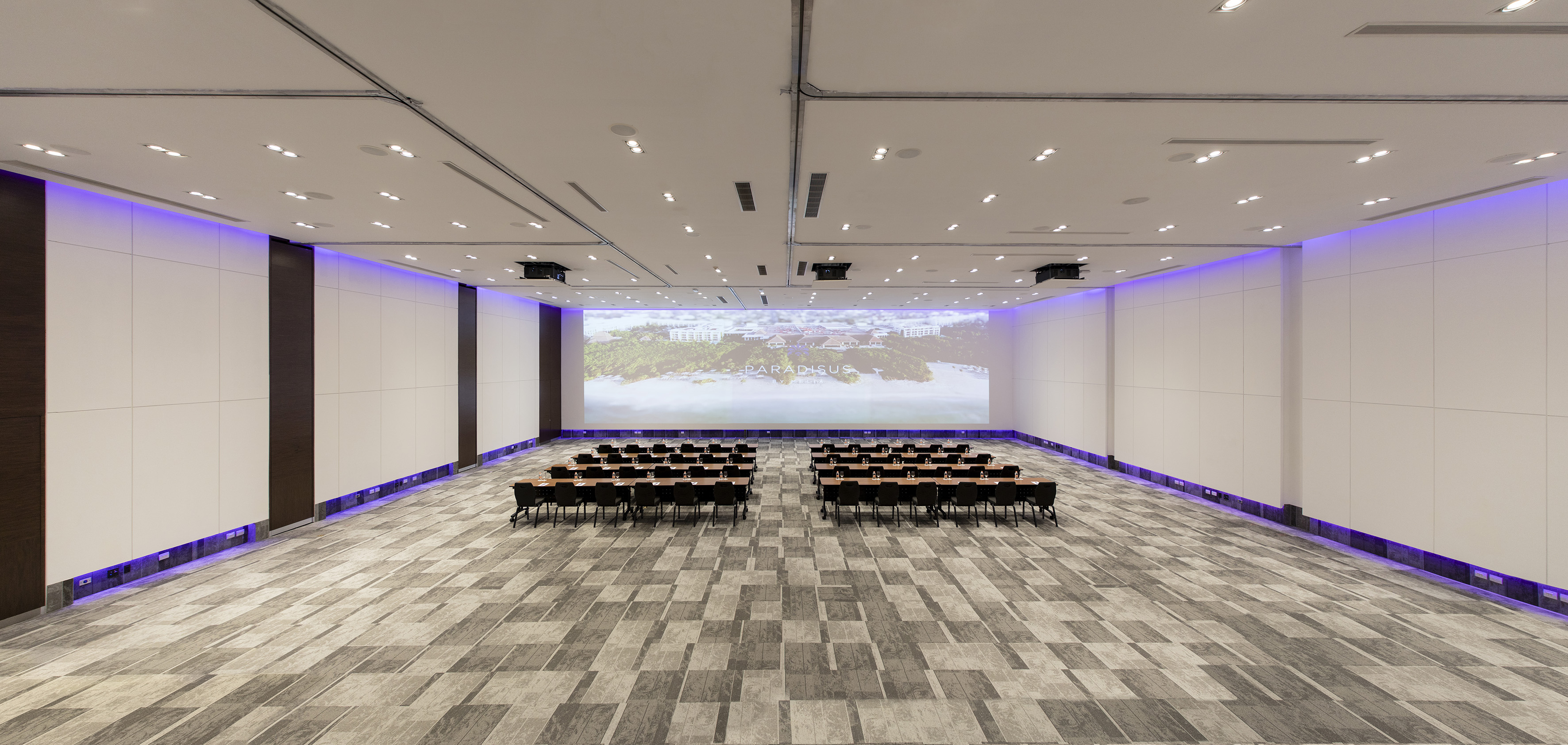 Modern conference room with tables, chairs, projector screen, and purple lighting.