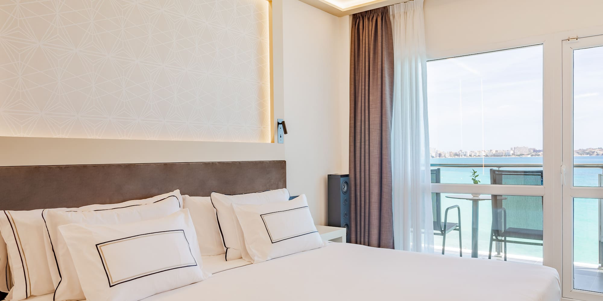 a bed with white pillows and a large window