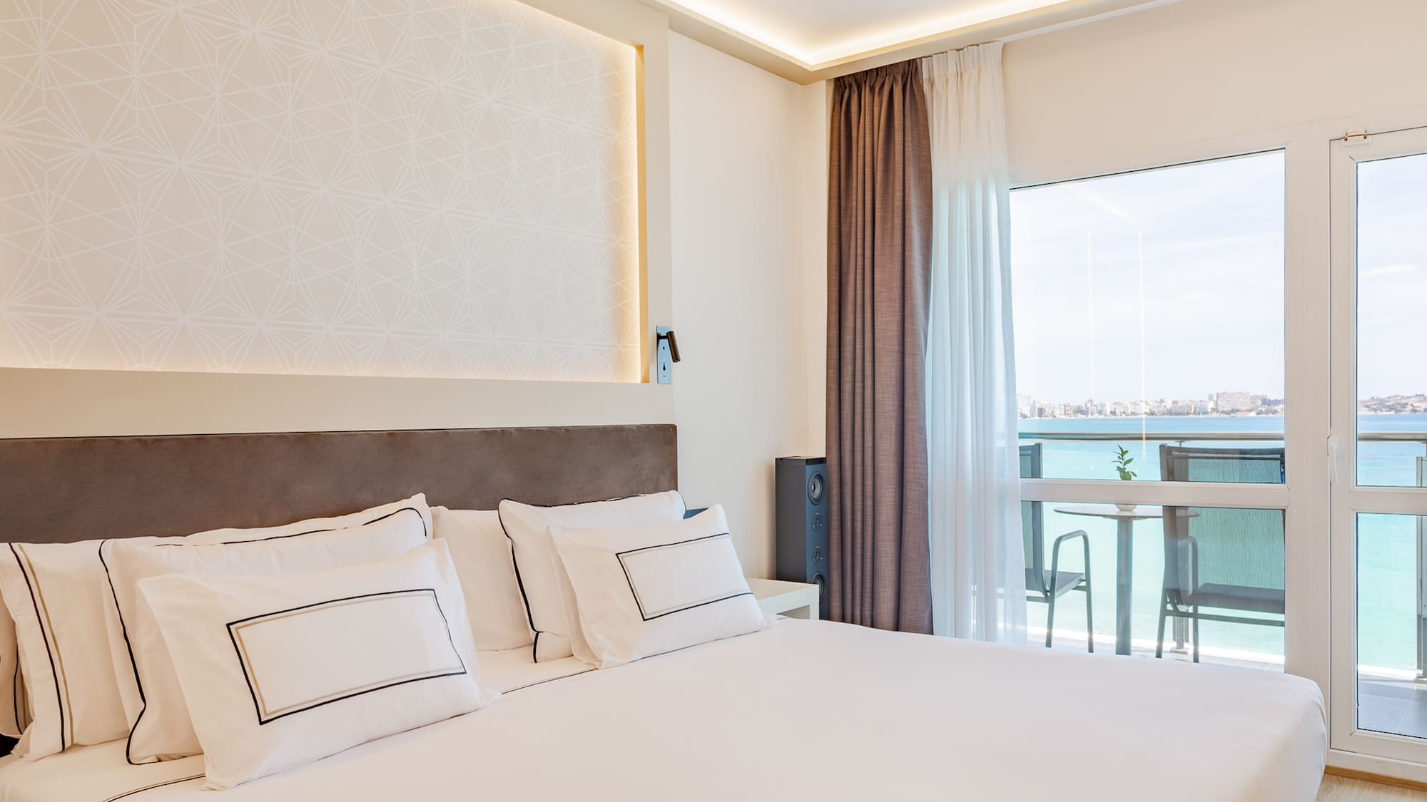 a bed with white pillows and a large window