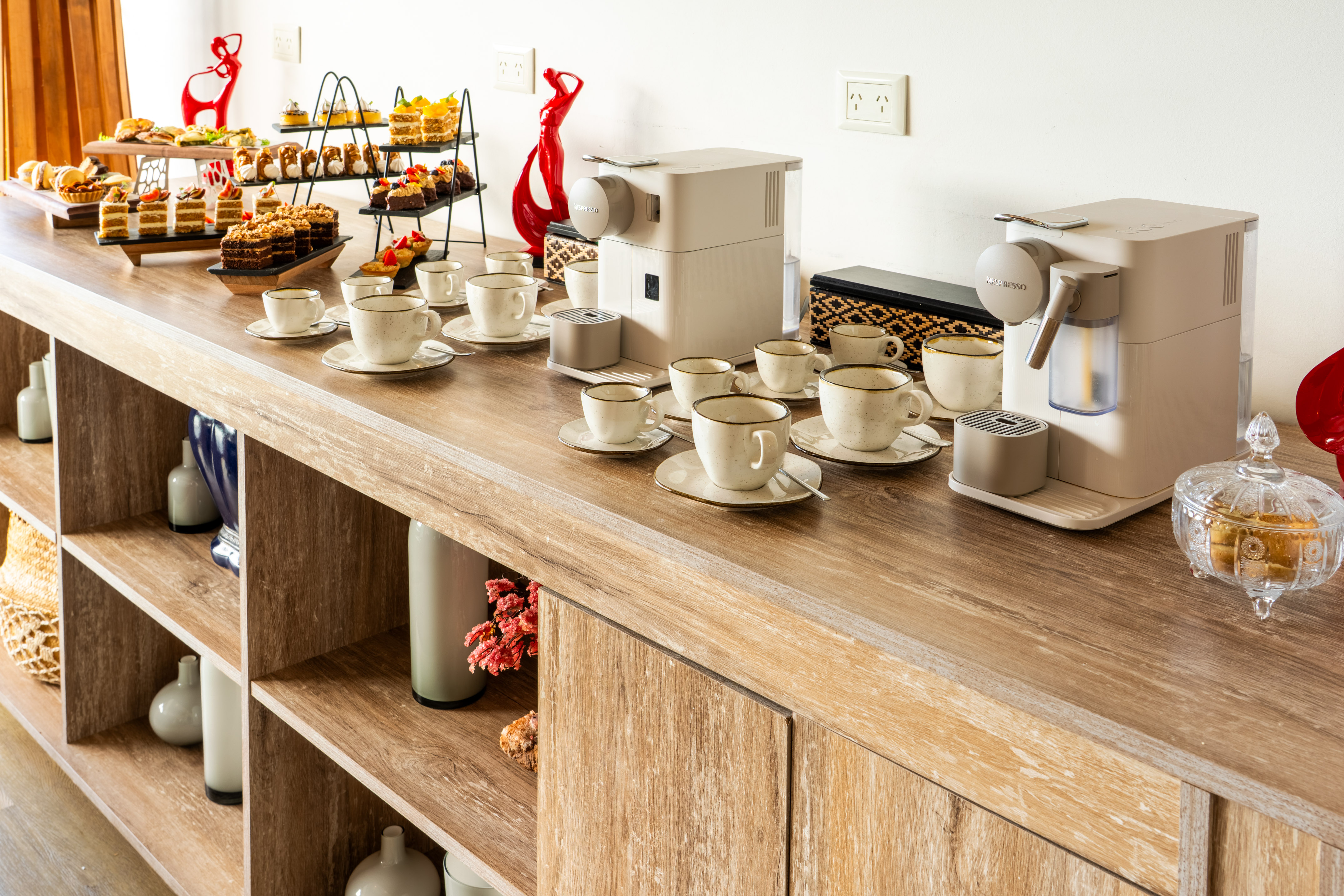 Nespresso coffee station, dessert buffet with cakes and pastries on wooden counter.