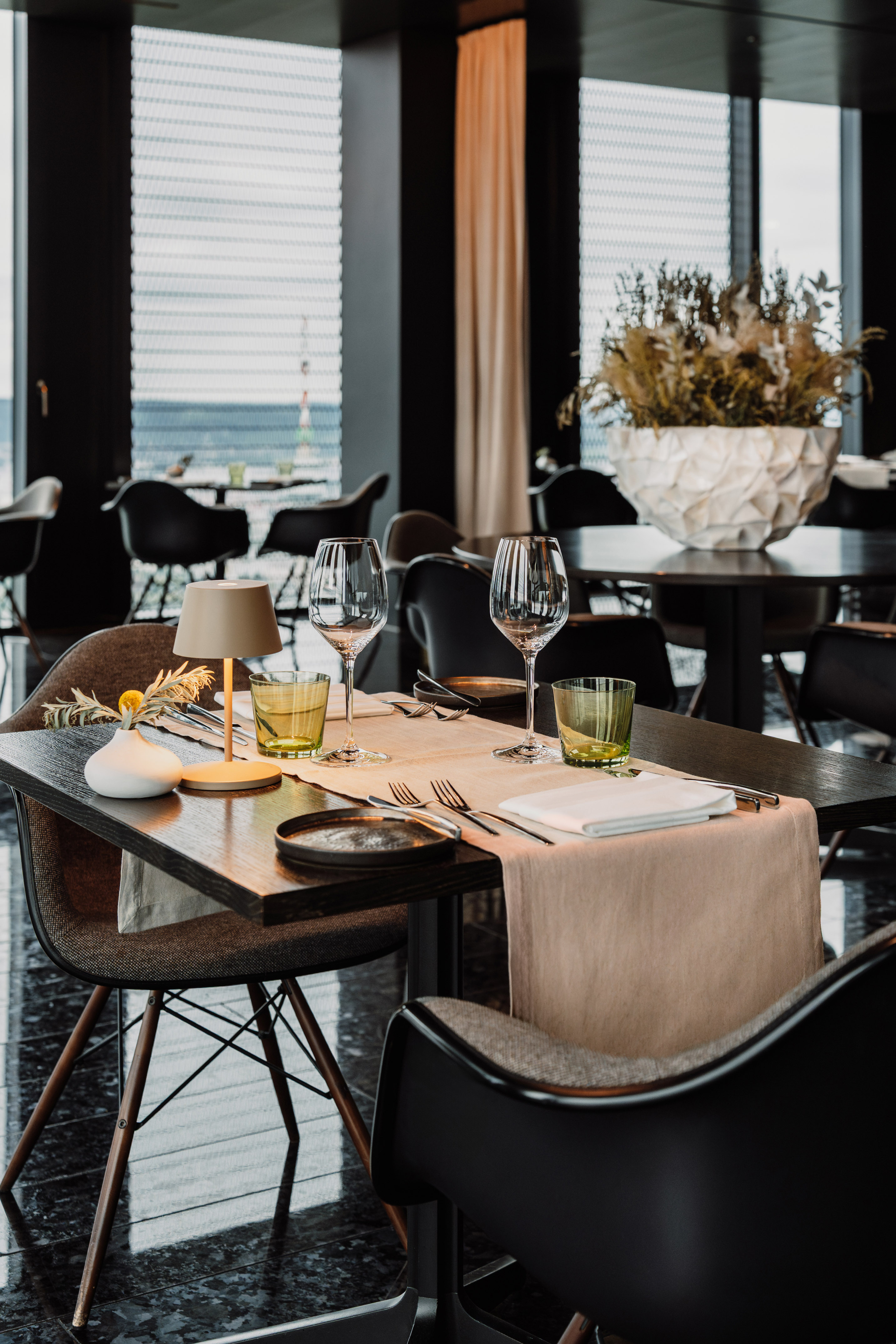 Set restaurant dining table with wine glasses, modern decor, and window view.