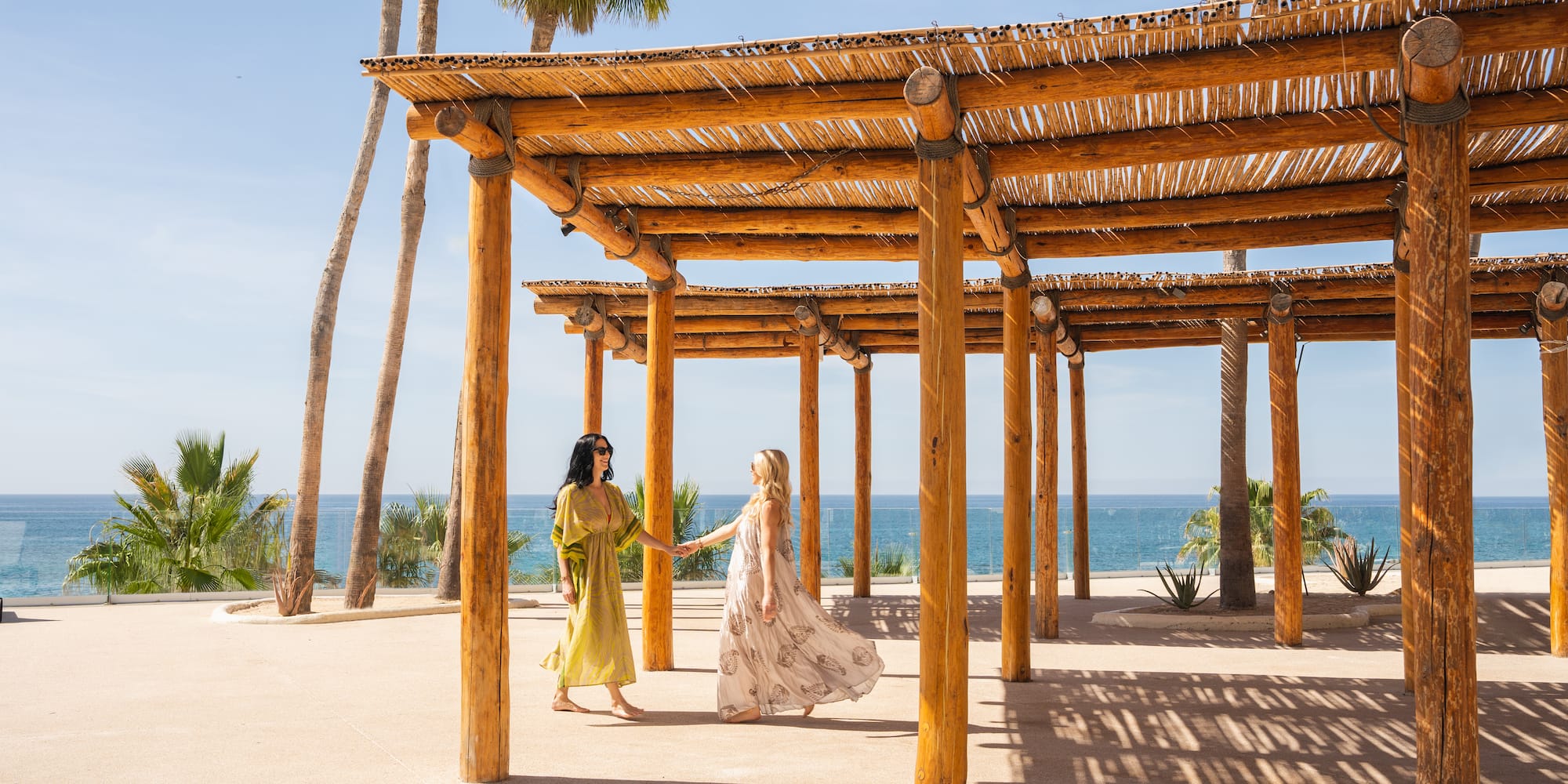 two women holding hands under a wooden structure