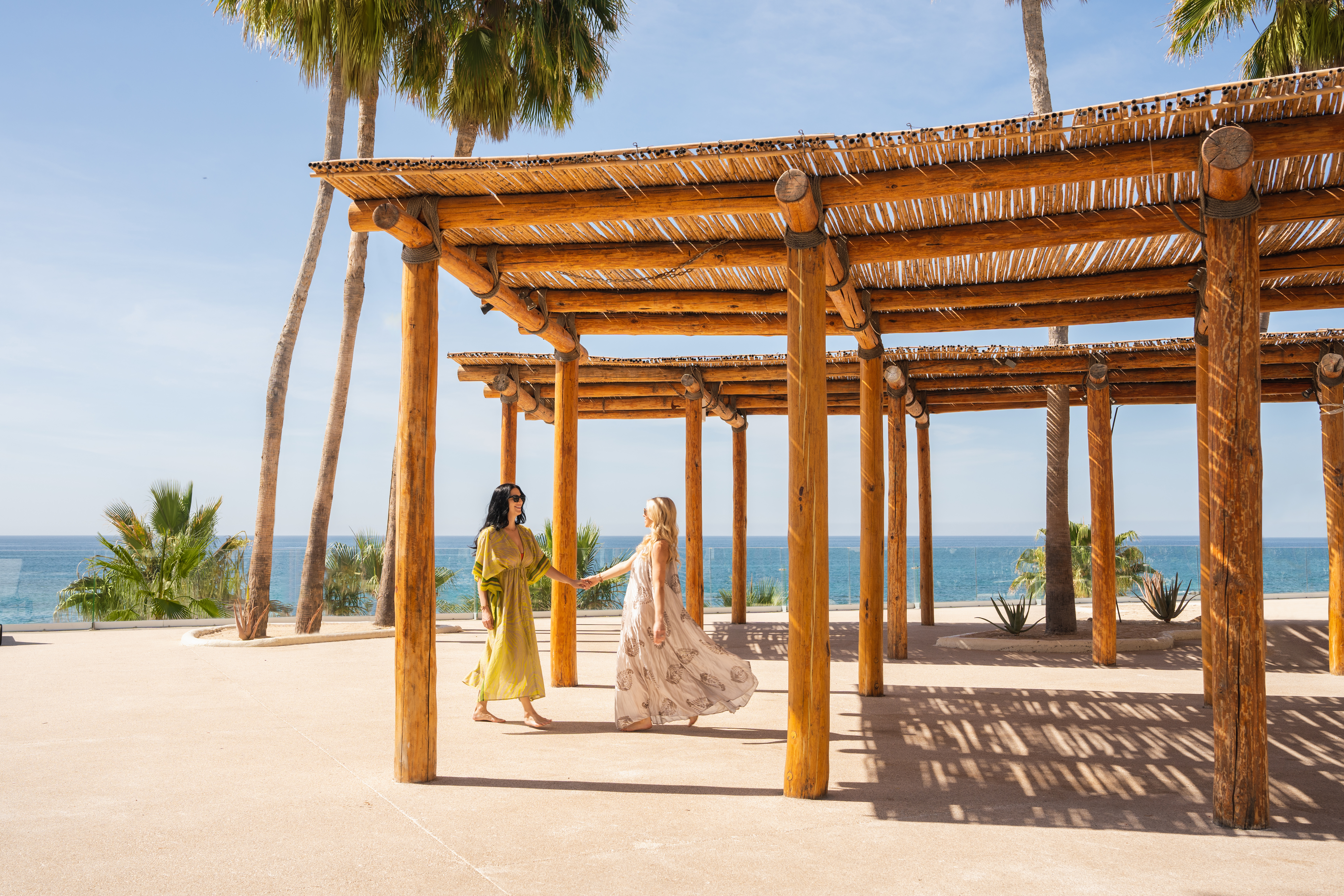 two women holding hands under a wooden structure