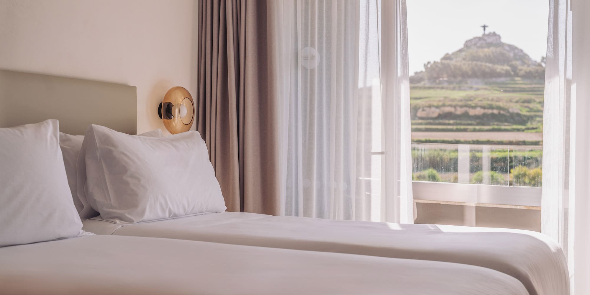 two beds in a room with a view of a hill and a hill