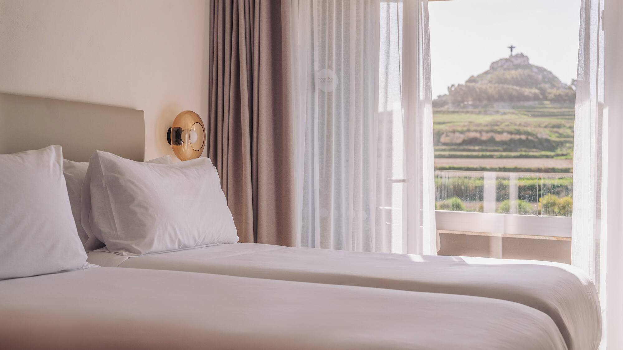 two beds in a room with a view of a hill and a hill