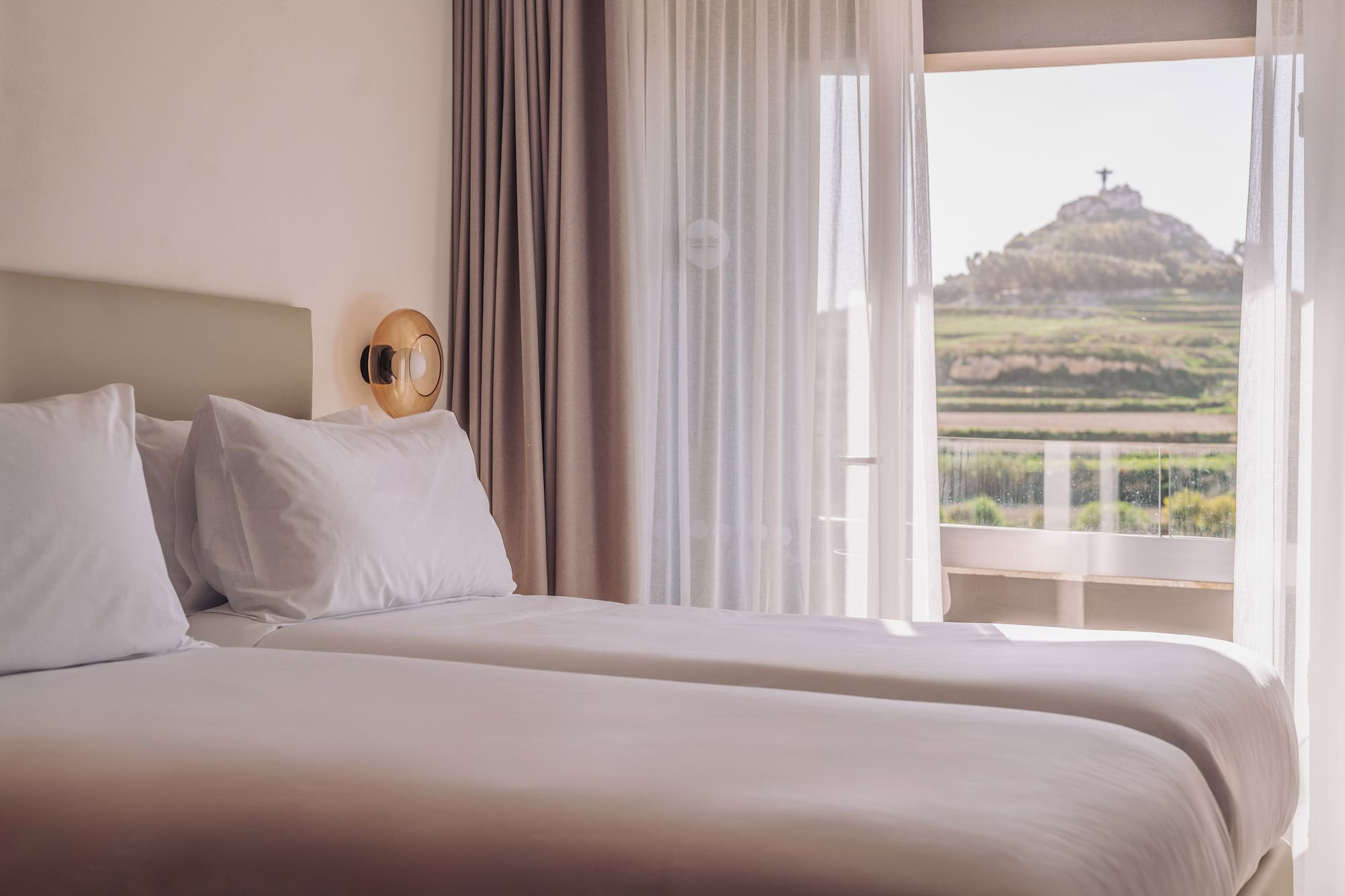 two beds in a room with a view of a hill and a hill