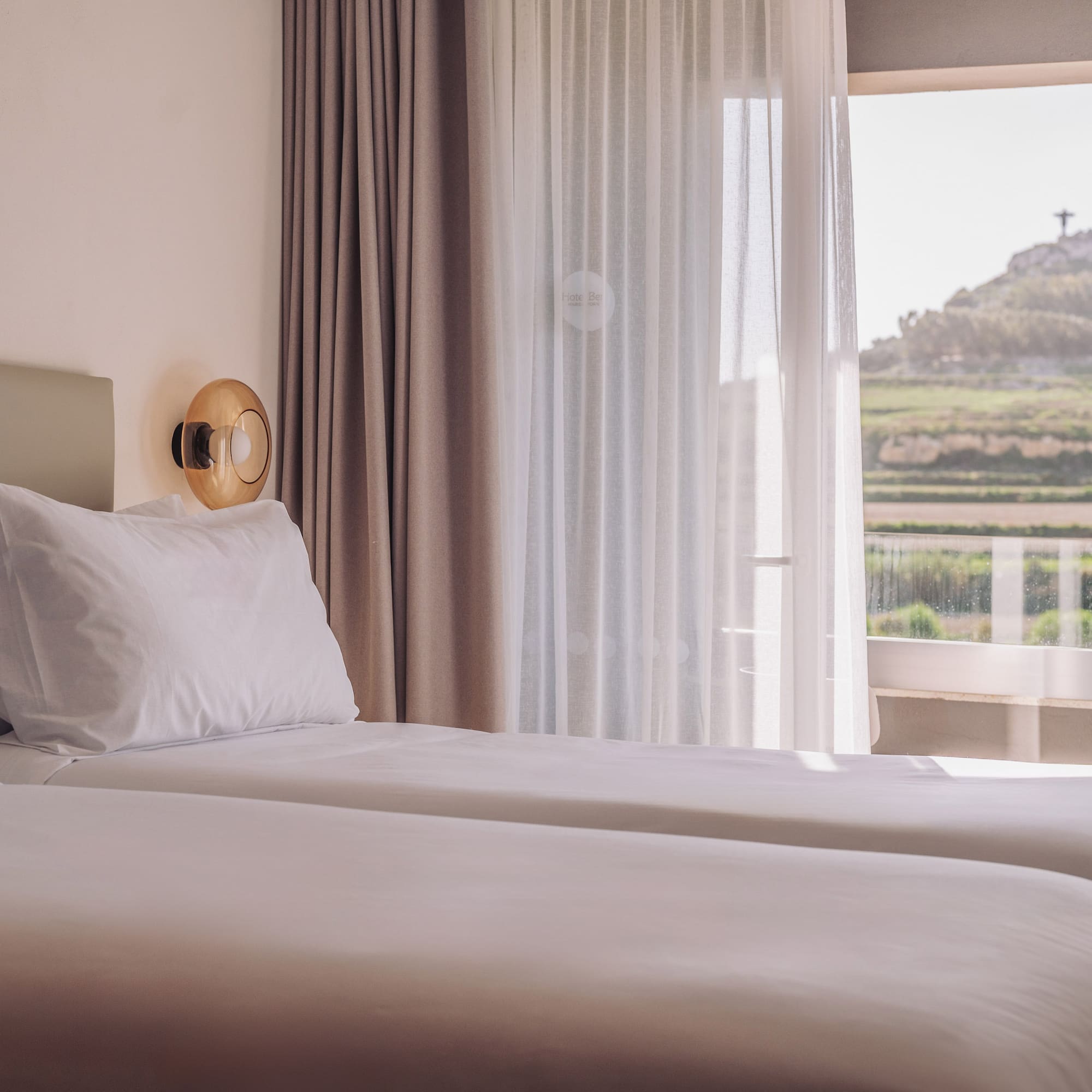 two beds in a room with a view of a hill and a hill