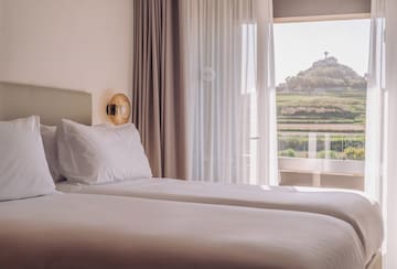 two beds in a room with a view of a hill and a hill