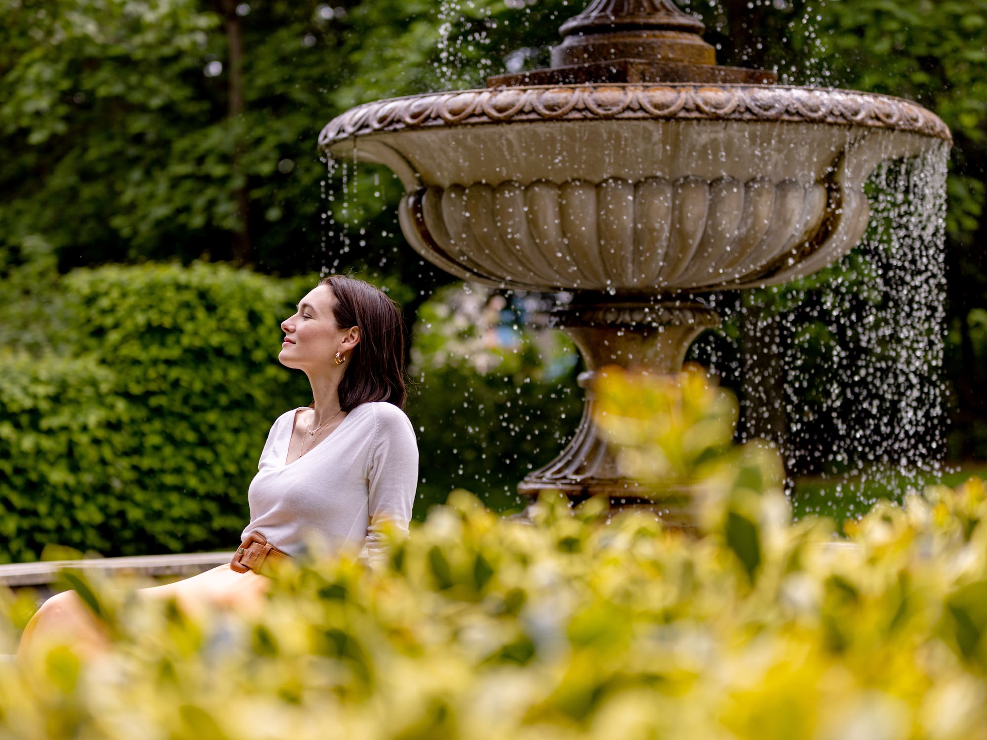 a woman sitting in front of a fountain