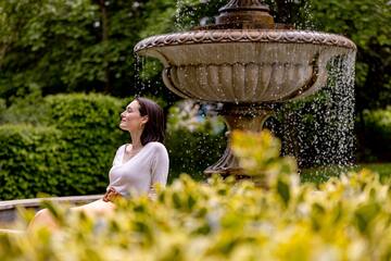 a woman sitting in front of a fountain