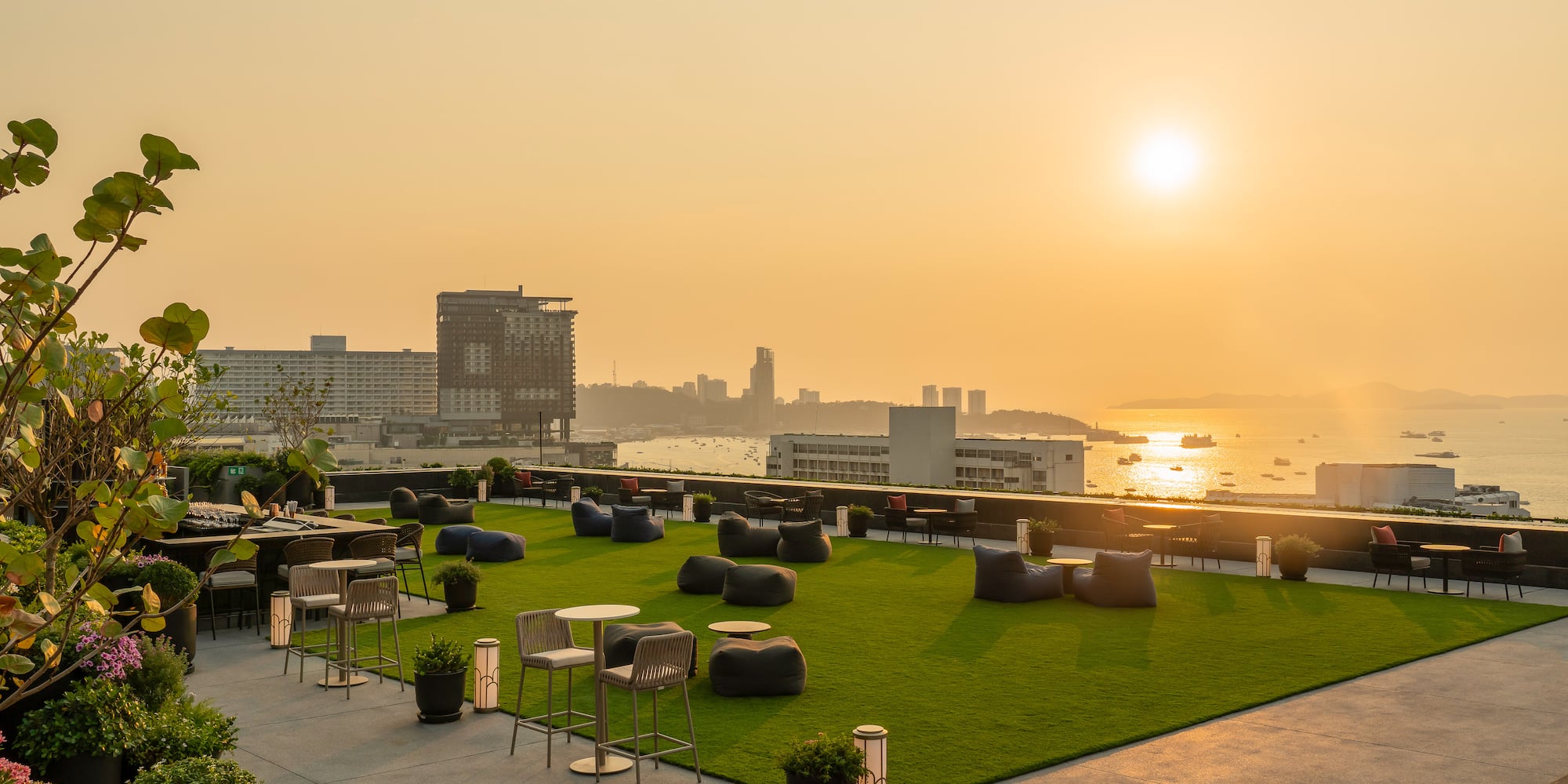 a rooftop patio with chairs and tables and a city in the background