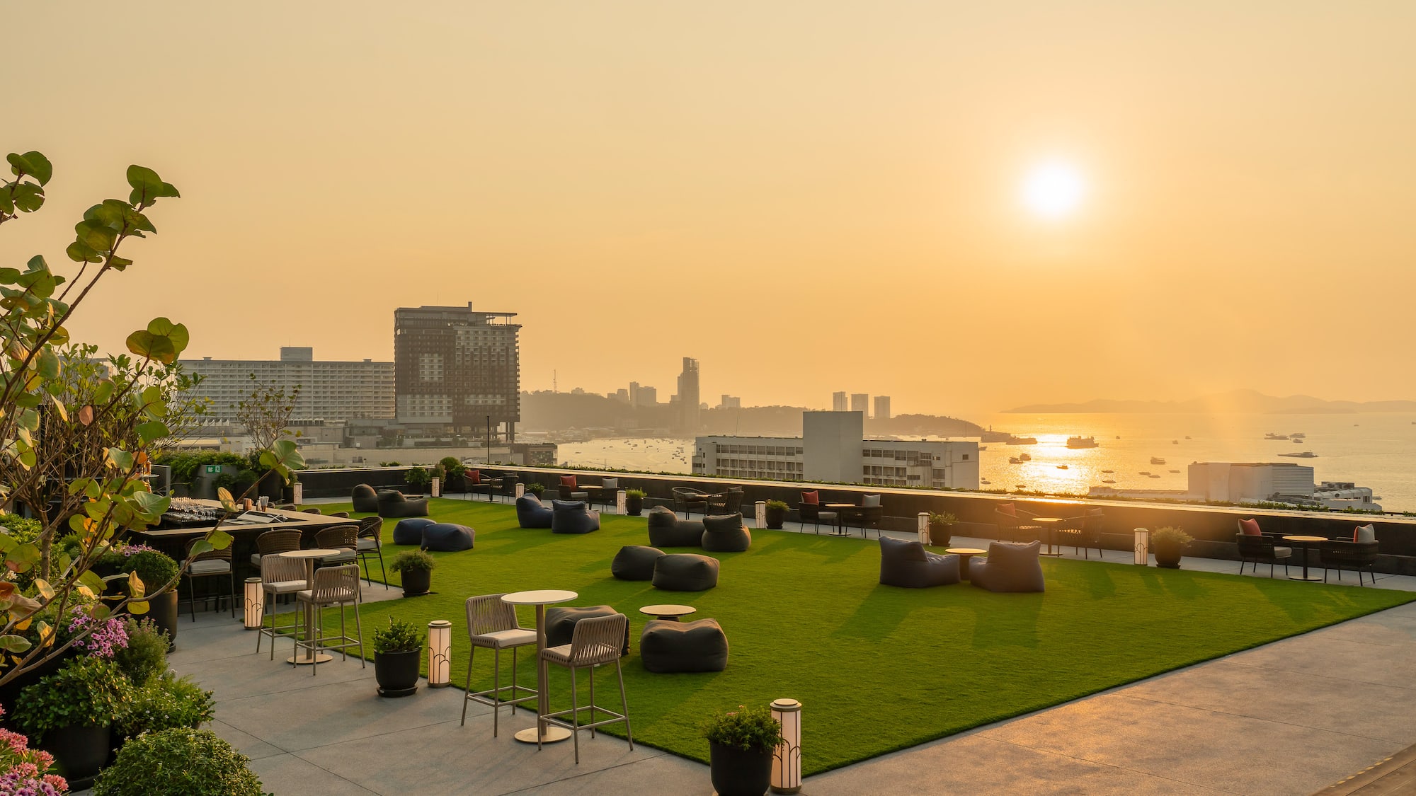 a rooftop patio with chairs and tables and a city in the background