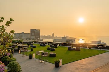 a rooftop patio with chairs and tables and a city in the background