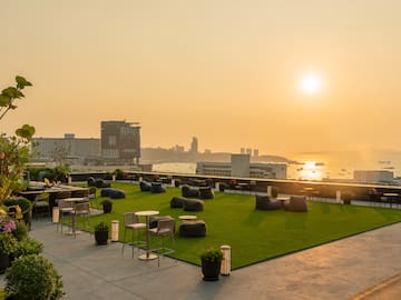 a rooftop patio with chairs and tables and a city in the background