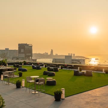 a rooftop patio with chairs and tables and a city in the background
