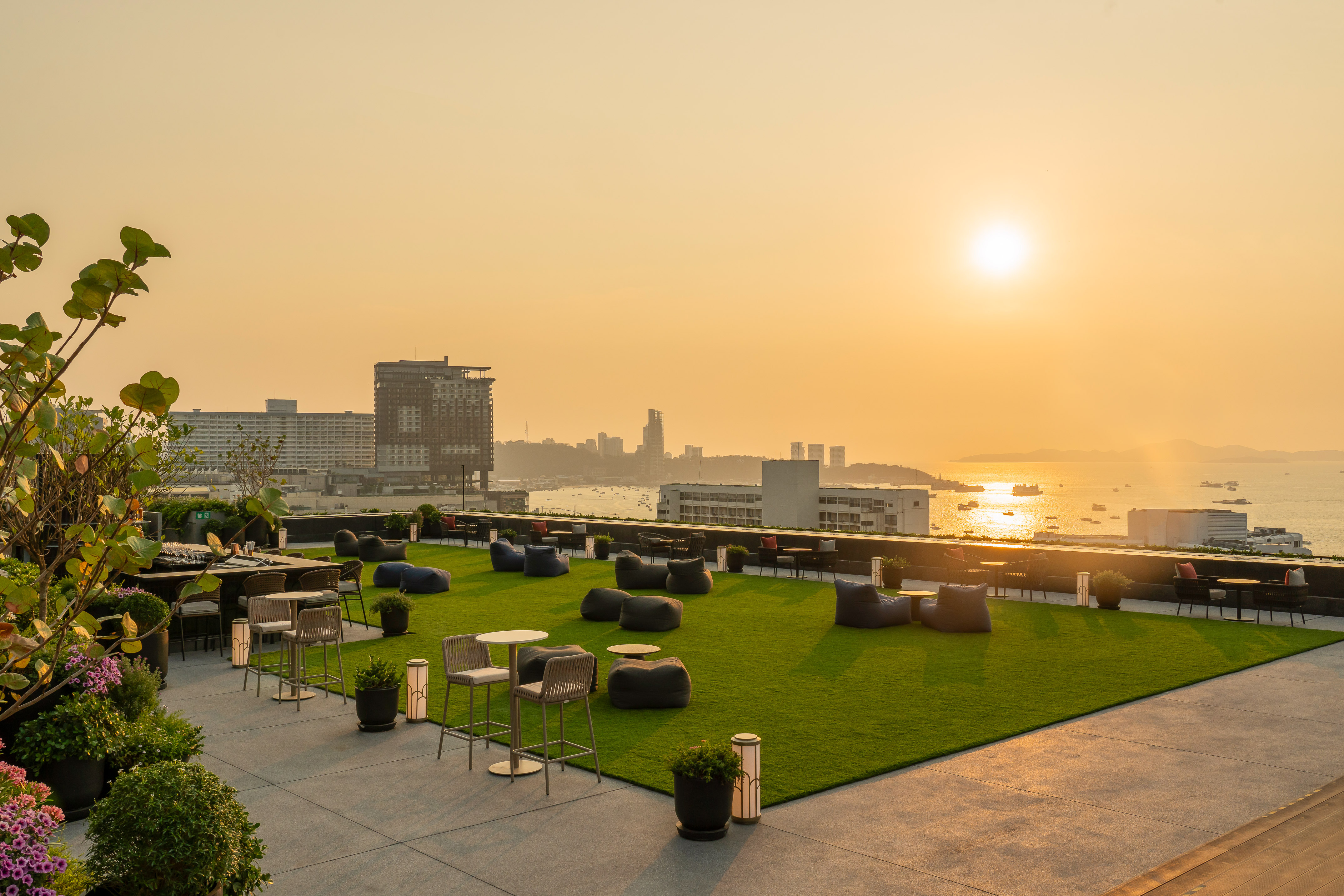 a rooftop patio with chairs and tables and a city in the background