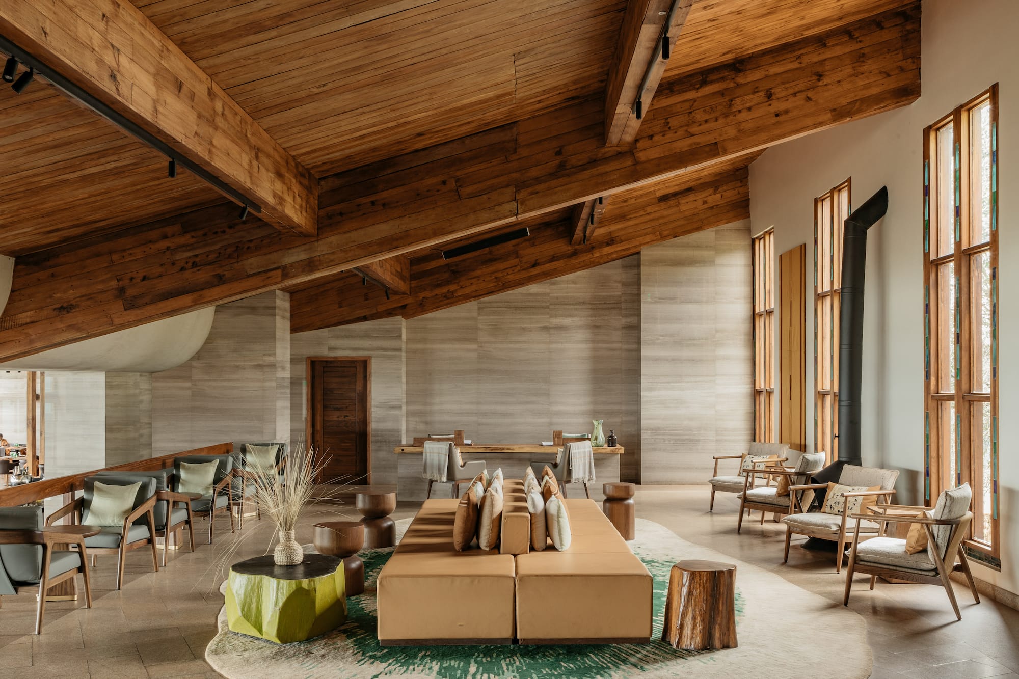 Modern hotel lobby with wood beams, stone walls, and lounge seating.