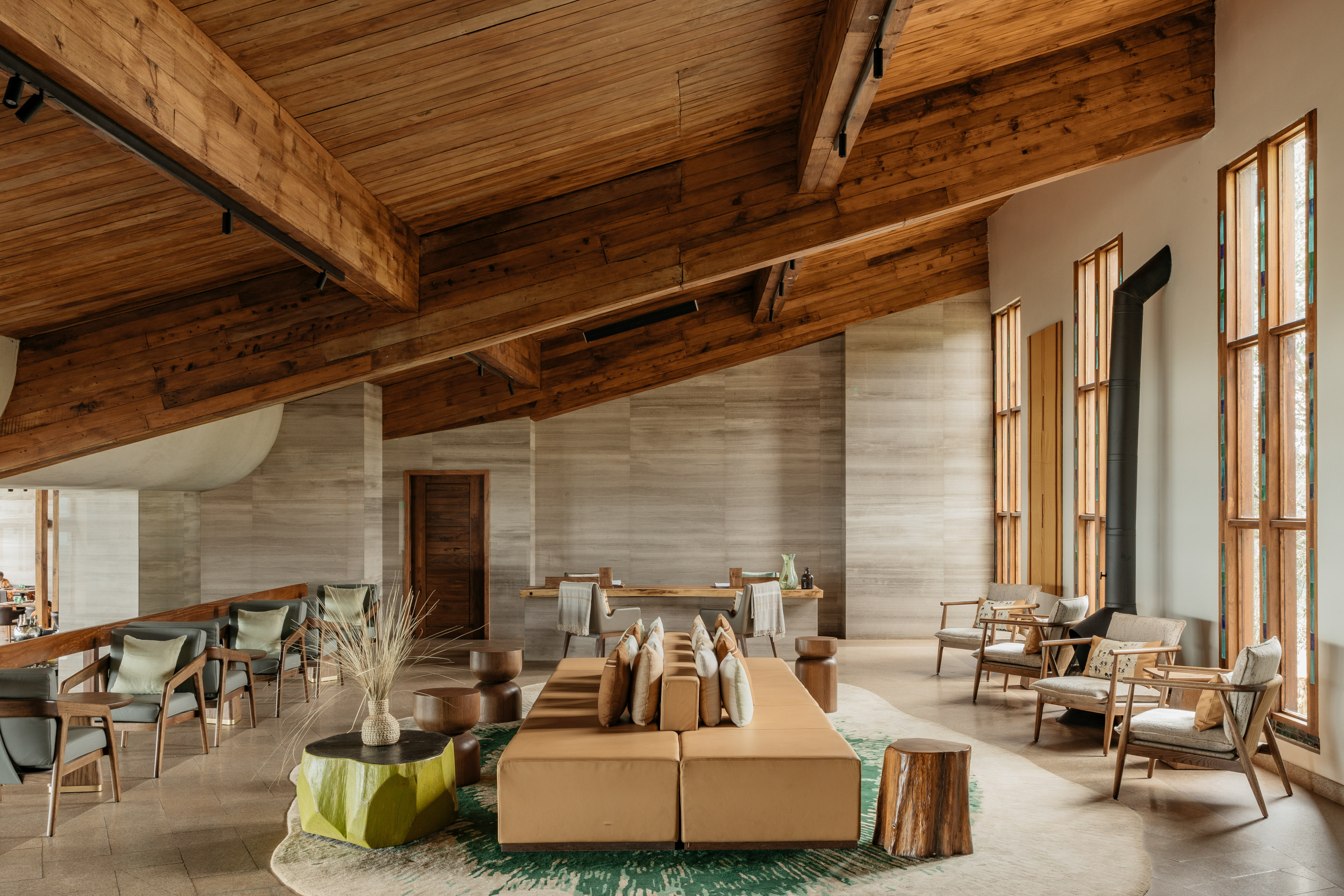 Modern hotel lobby with wood beams, stone walls, and lounge seating.