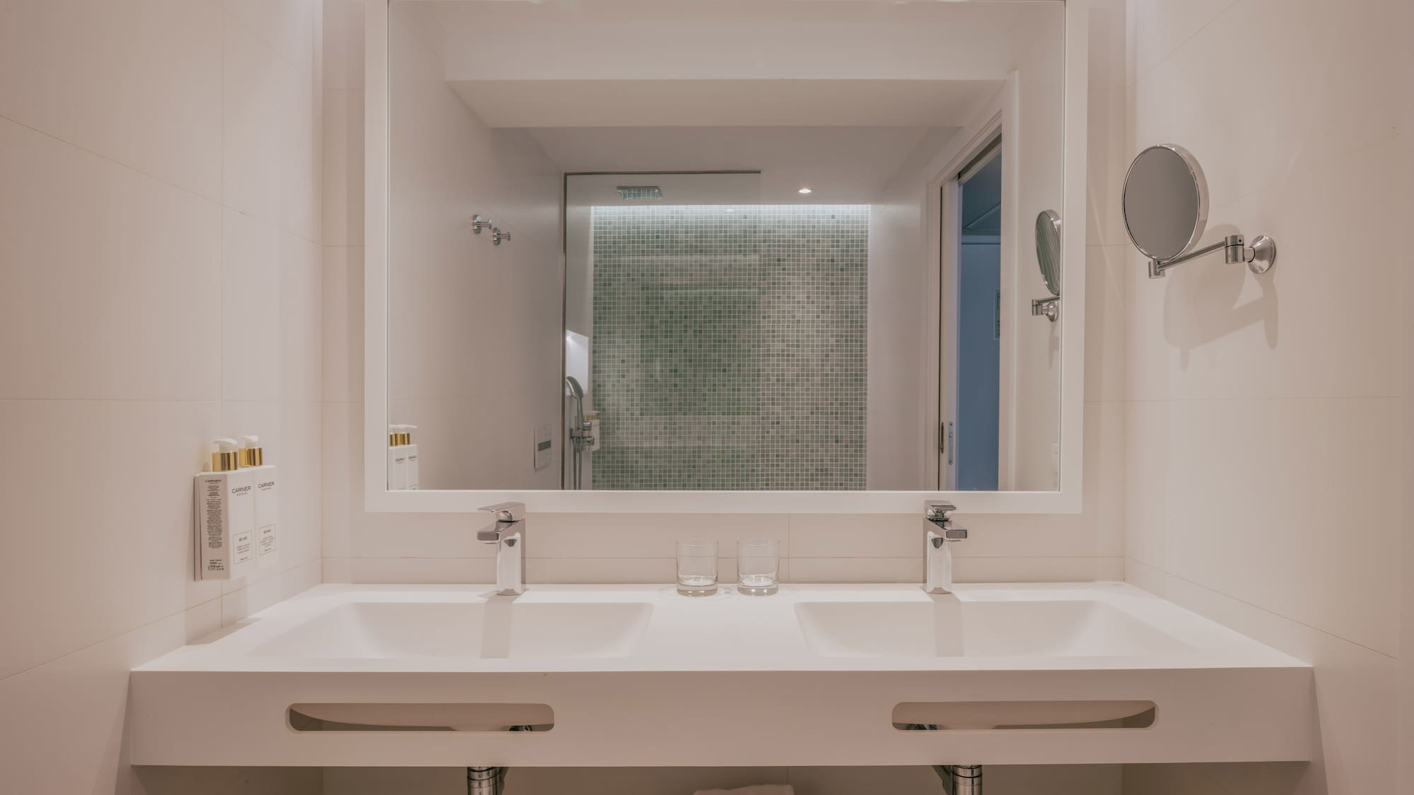 Modern bathroom: double vanity, large mirror, green mosaic shower.