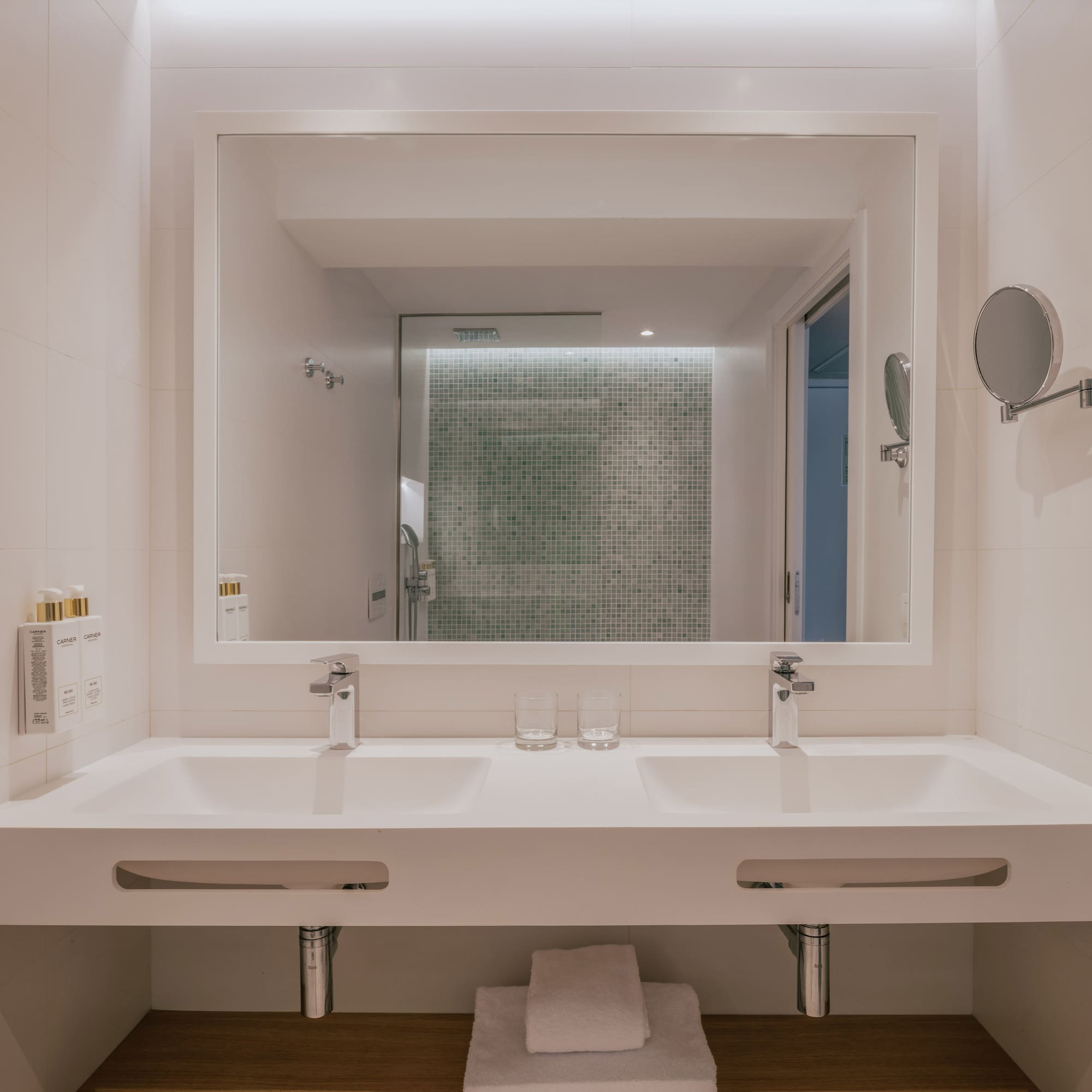 Modern bathroom: double vanity, large mirror, green mosaic shower.