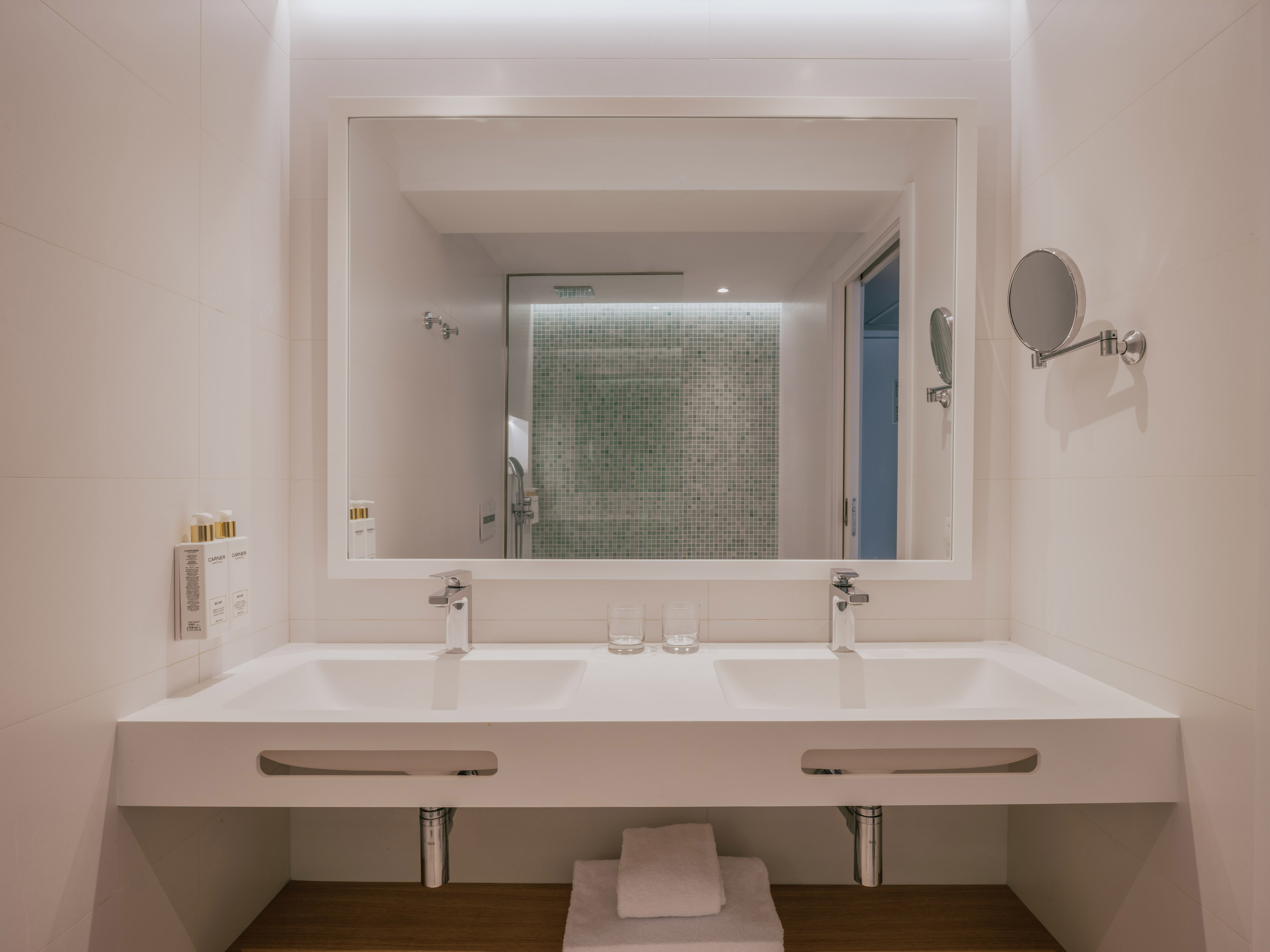 Modern bathroom: double vanity, large mirror, green mosaic shower.