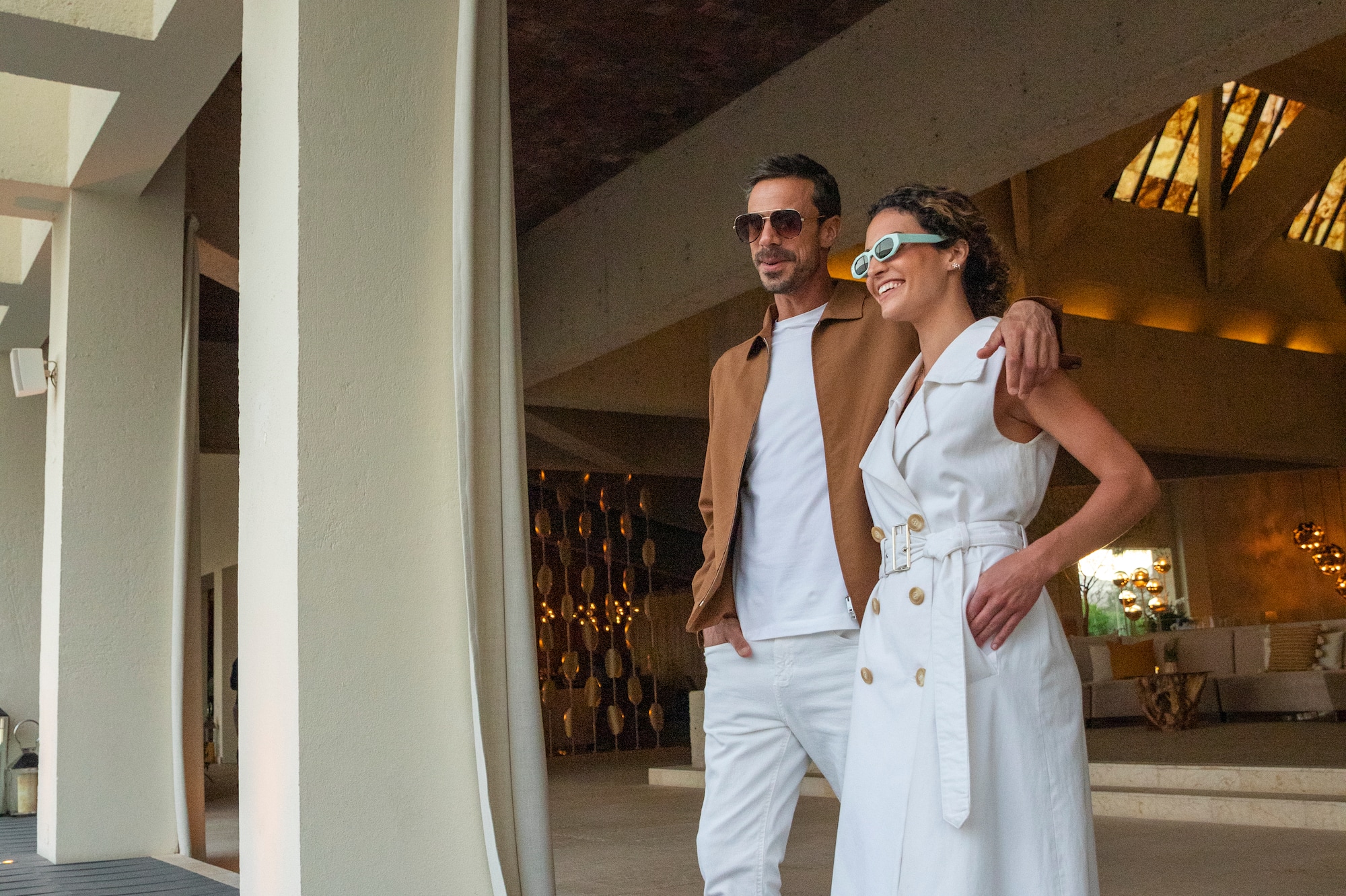 a man and woman standing in a room with columns