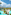 Resort with lagoon pools, palm trees, white buildings, distant ocean.