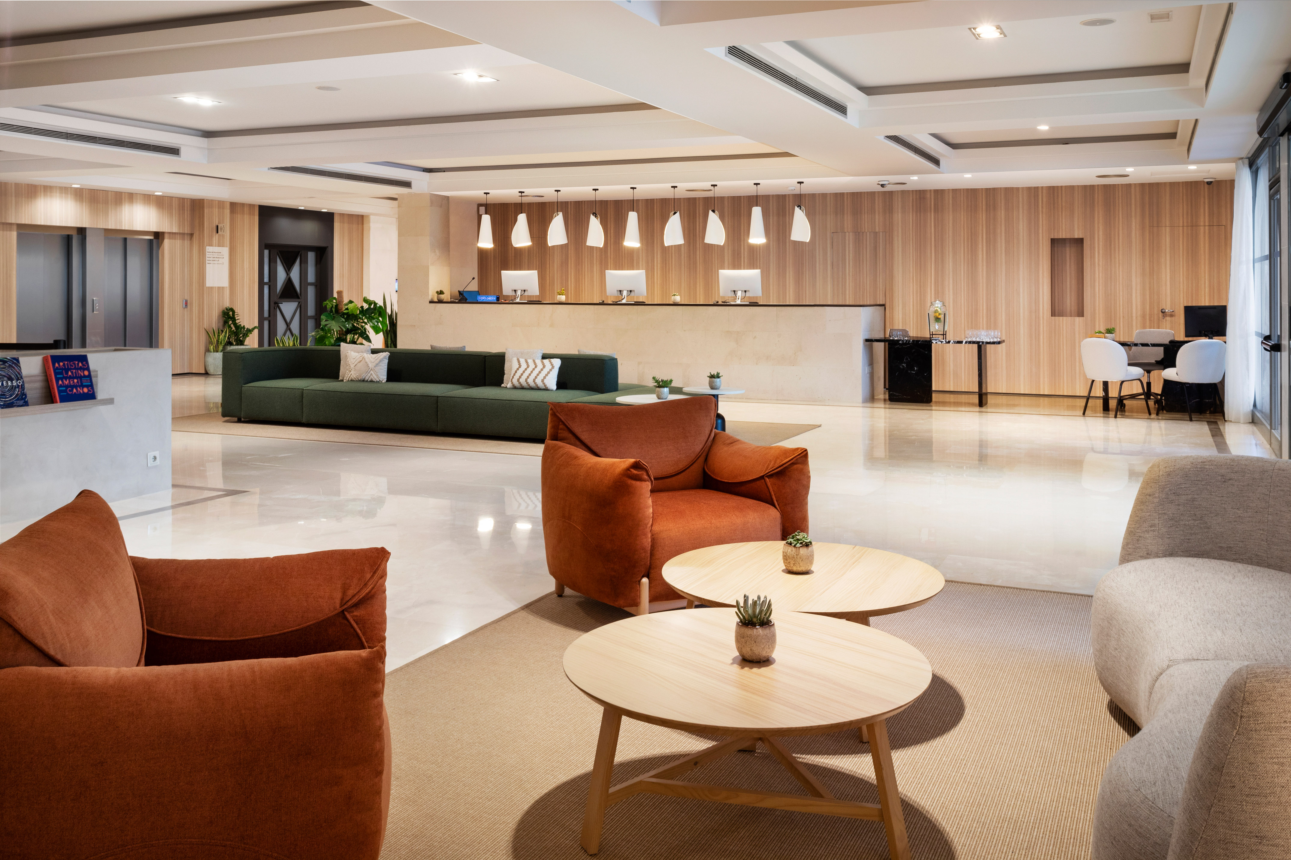 Hotel reception lobby with modern seating, wooden desk, and sleek design.