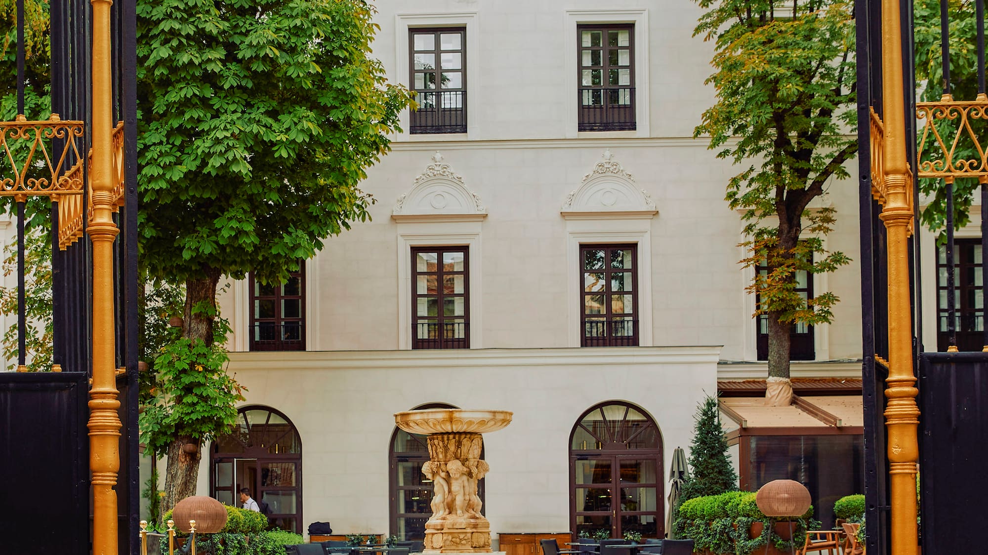 a gated courtyard with a fountain and tables and chairs