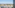 Elevated view of white villas, palm trees, and mountains against a clear sky.