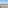 Elevated view of white villas, palm trees, and mountains against a clear sky.