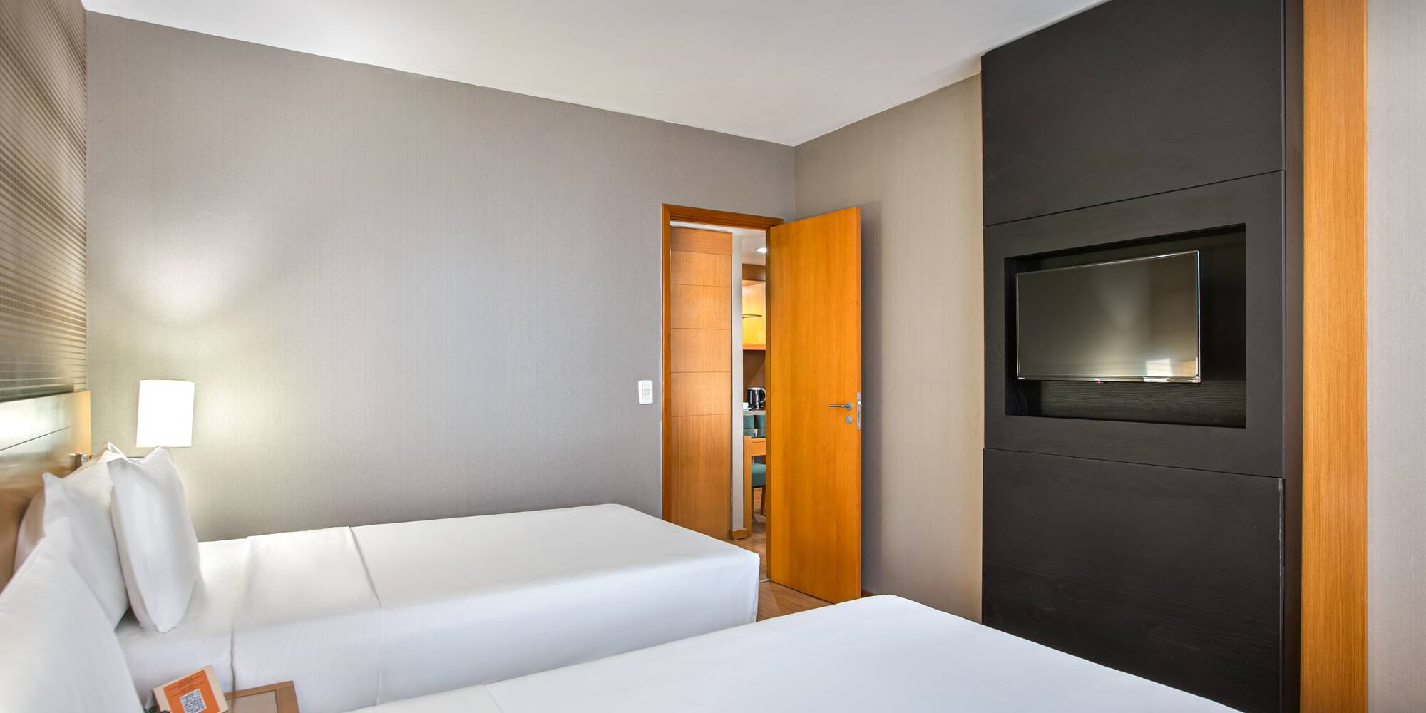 Hotel twin bedroom with contemporary decor and flat-screen TV.