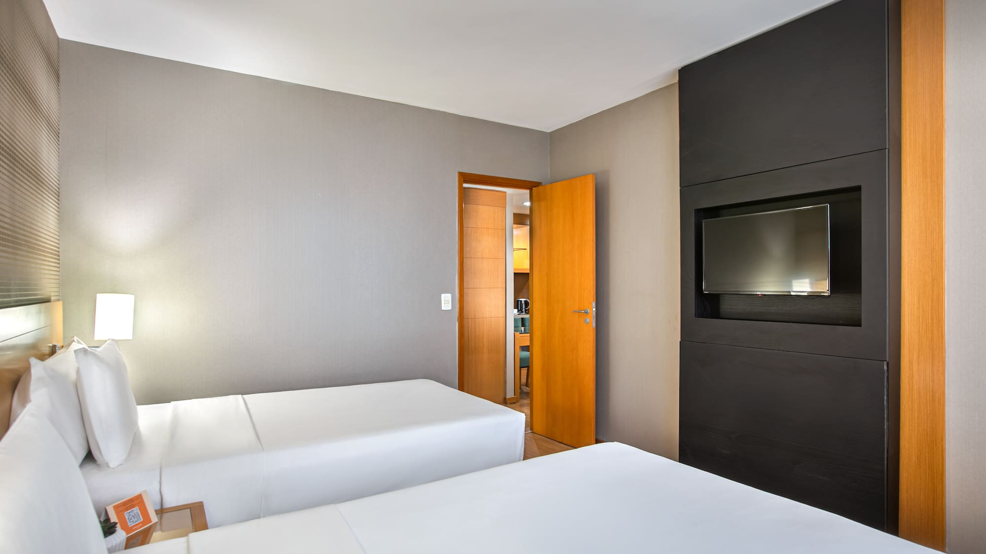 Hotel twin bedroom with contemporary decor and flat-screen TV.