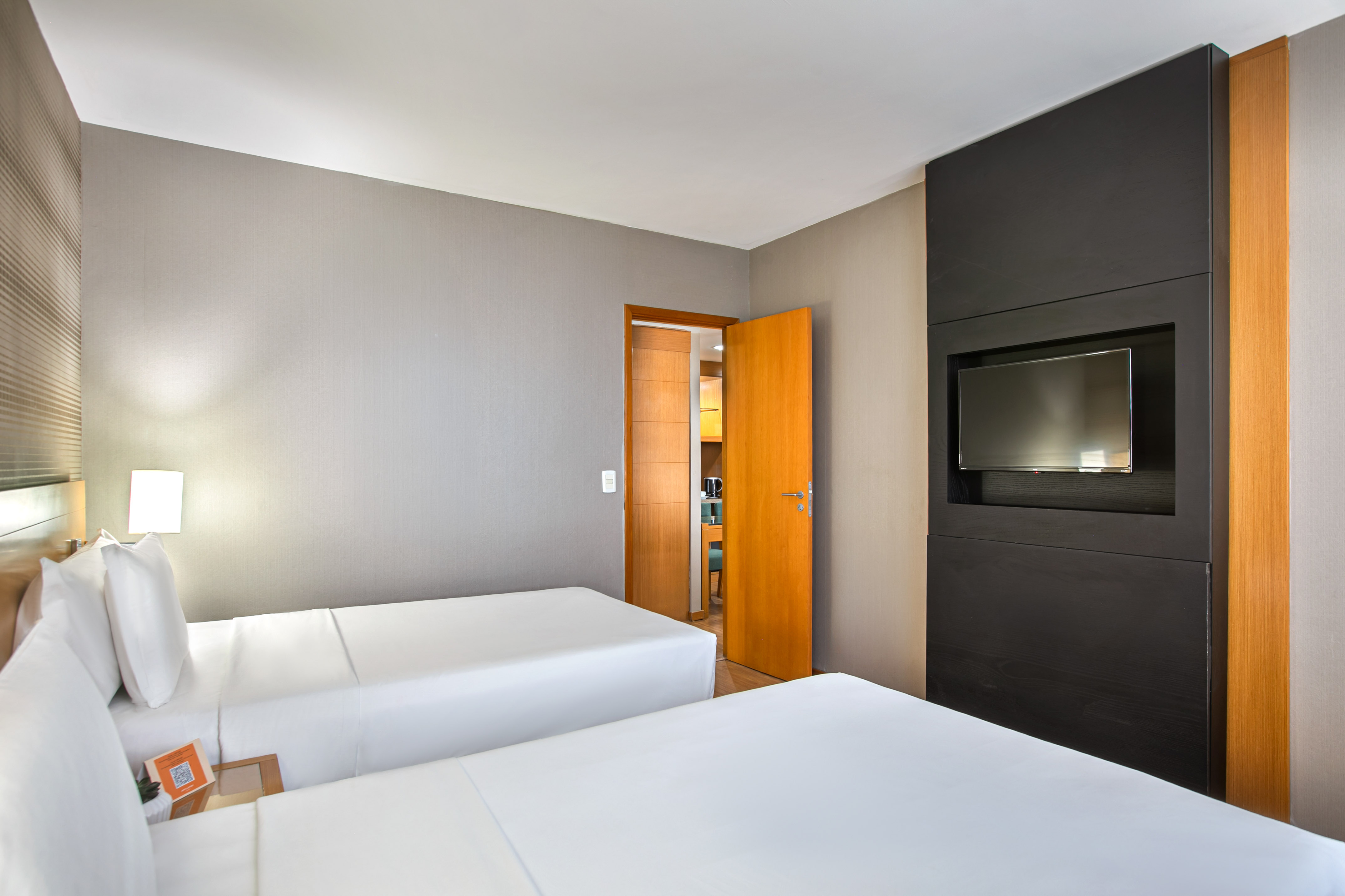 Hotel twin bedroom with contemporary decor and flat-screen TV.
