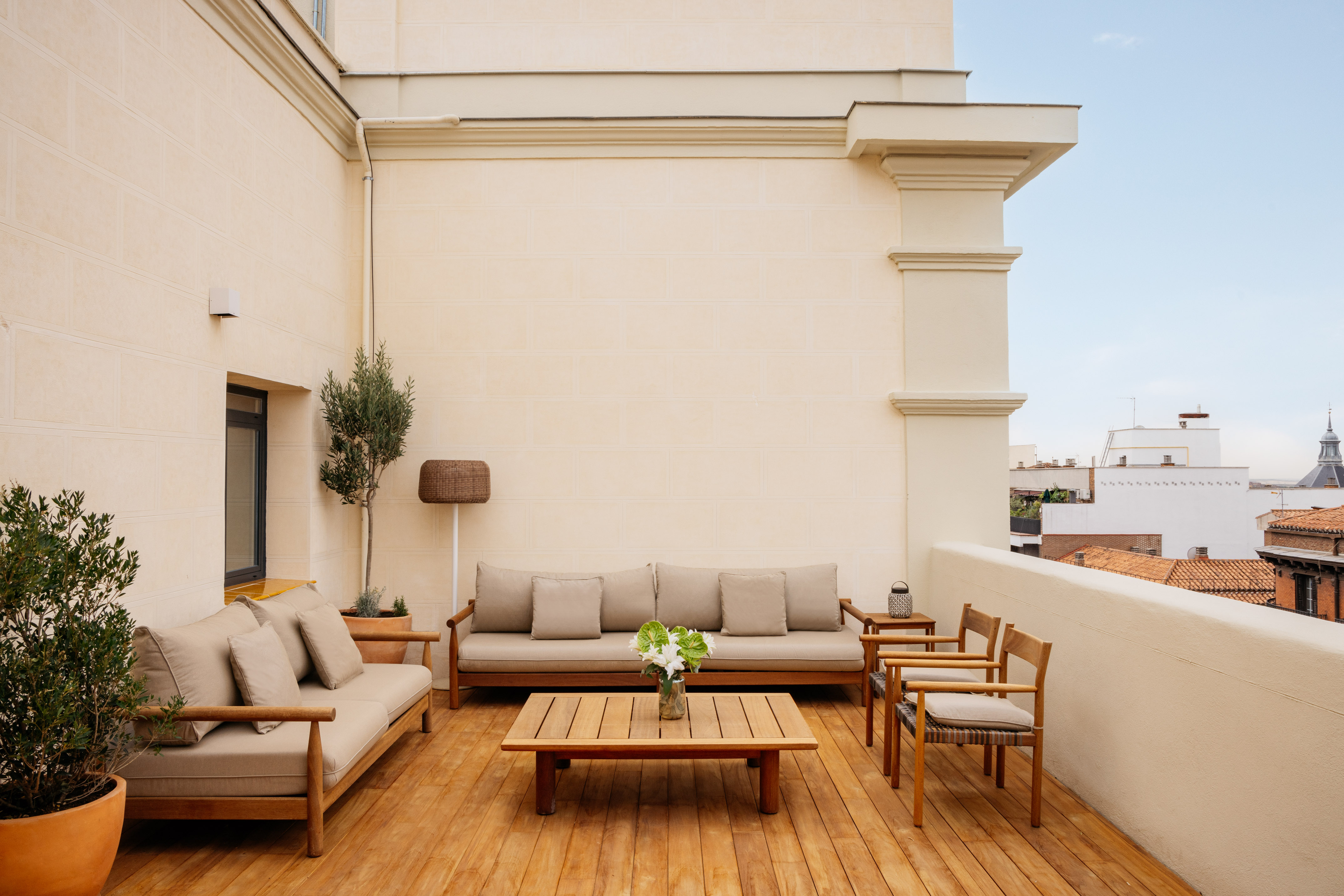 Modern rooftop terrace, wooden deck, outdoor sofas, plants, city view.