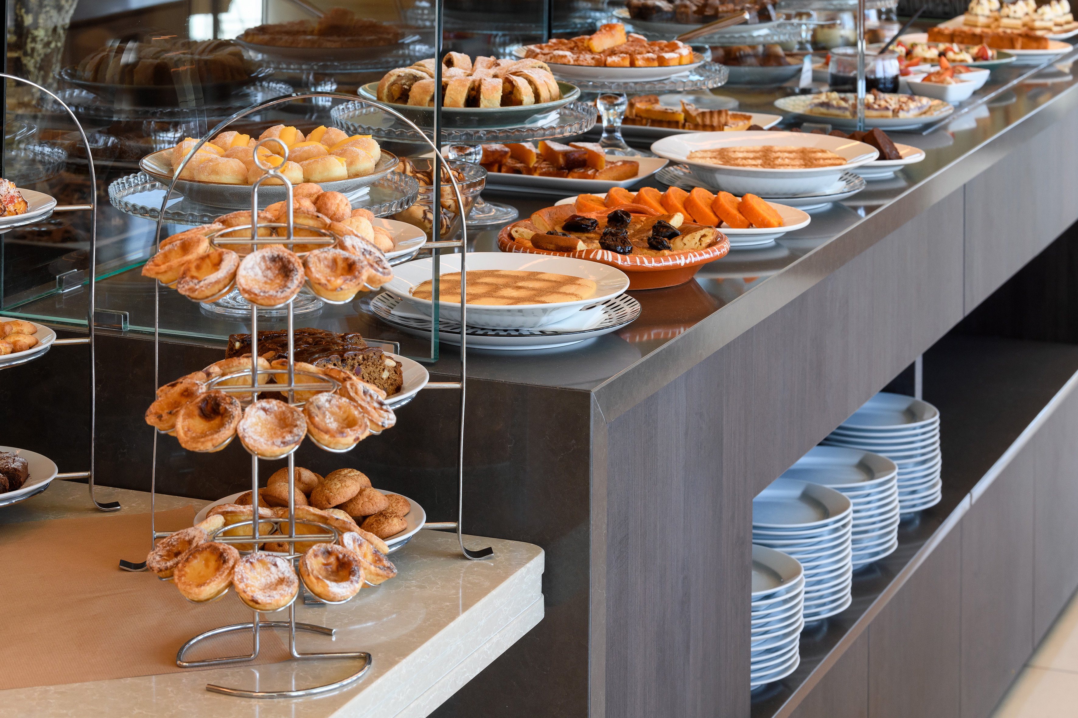 Hotel breakfast buffet: sweet pastries, cakes, tarts, and sliced fruit.