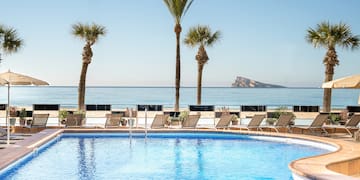 a pool with palm trees and a beach in the background