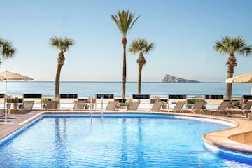 a pool with palm trees and a beach in the background