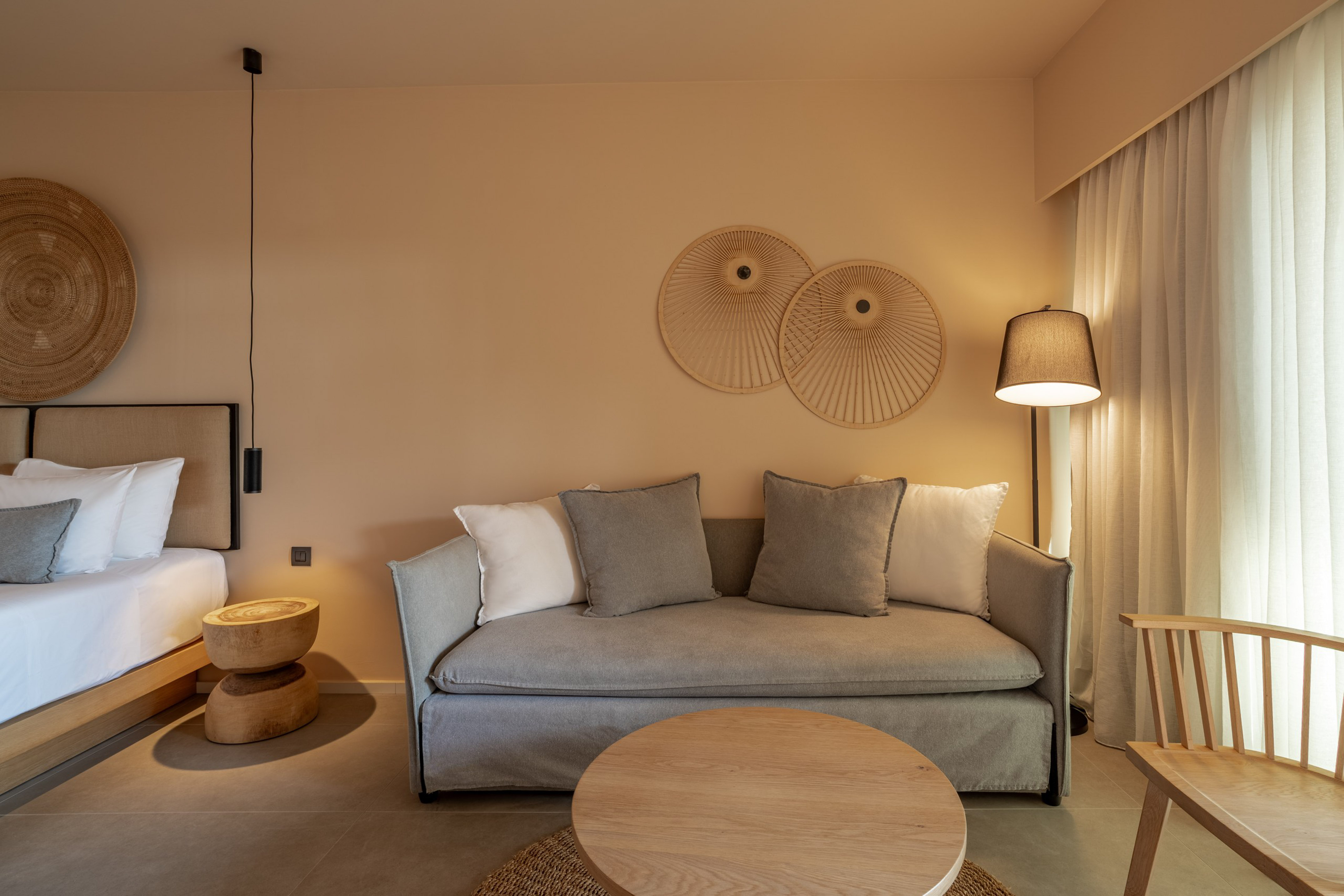 Modern hotel suite with neutral decor, grey sofa, and natural wood furniture.