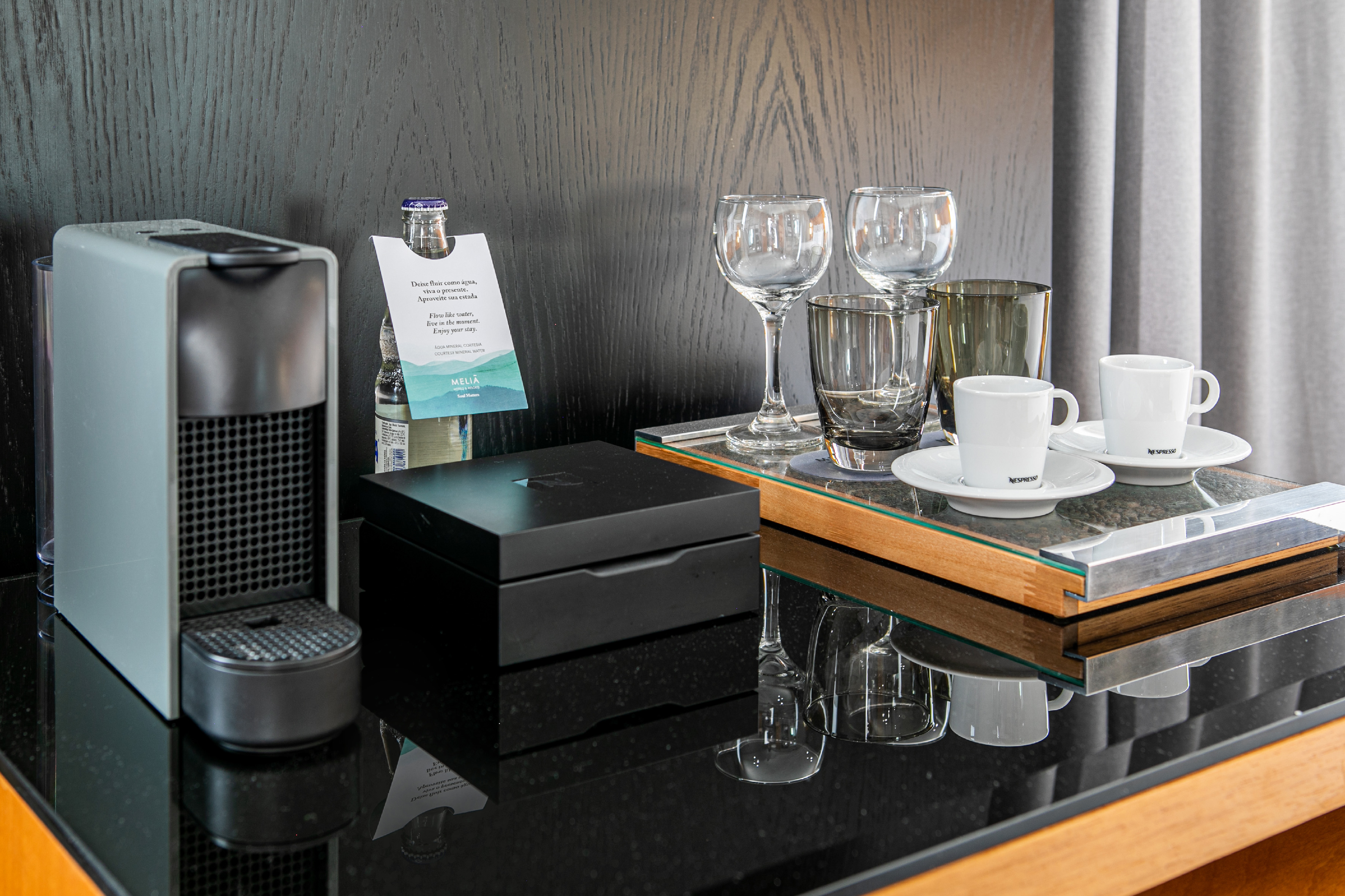 Hotel room Nespresso coffee station with machine, cups, glasses, and Meliá water.