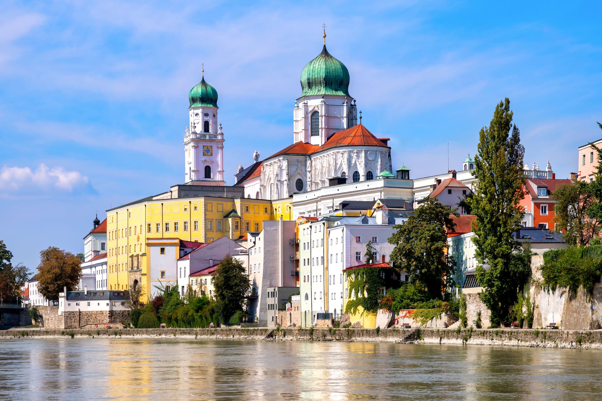 Catedral de Passau con cúpulas verdes y edificios coloridos a orillas del río, Alemania.