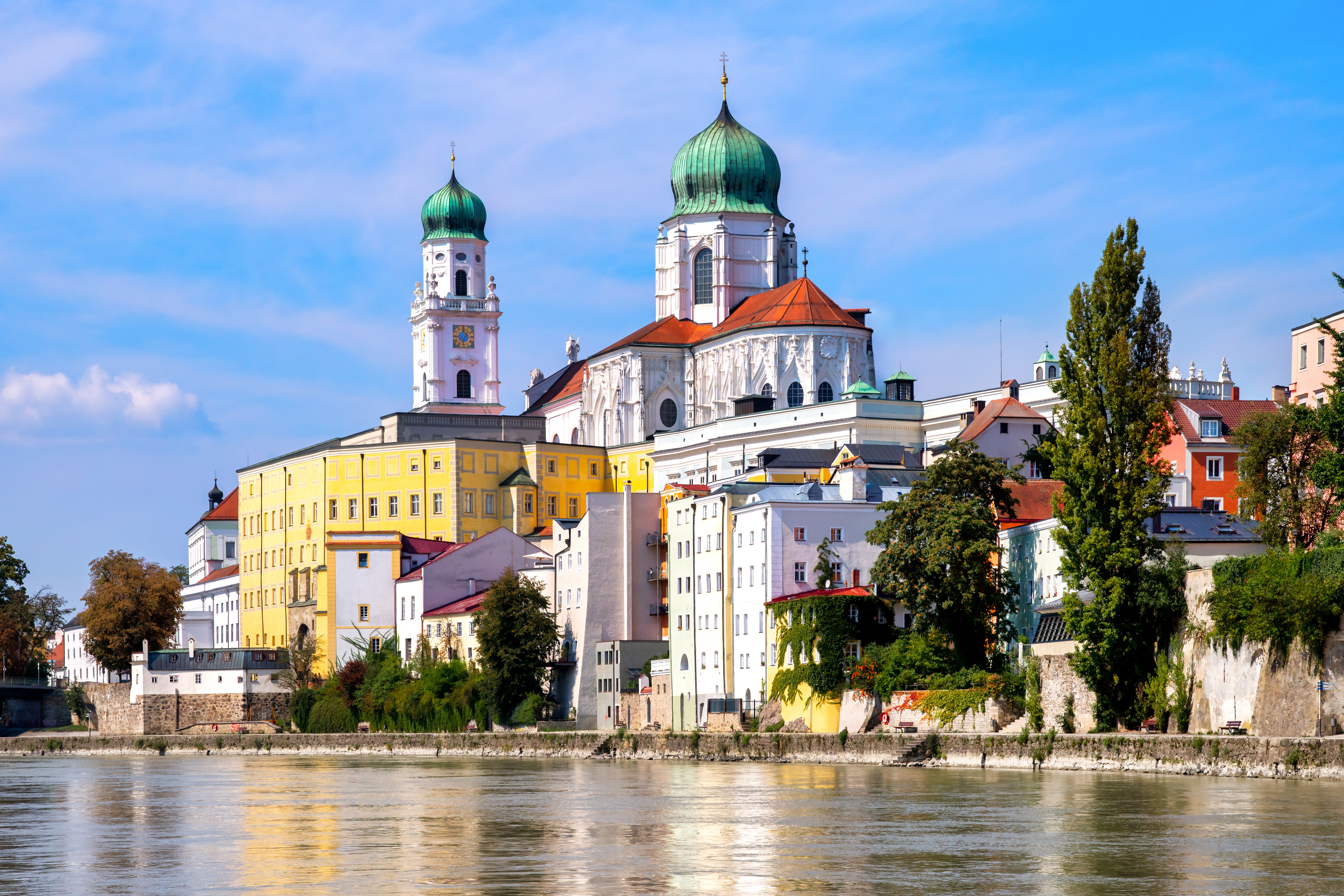 Catedral de Passau con cúpulas verdes y edificios coloridos a orillas del río, Alemania.
