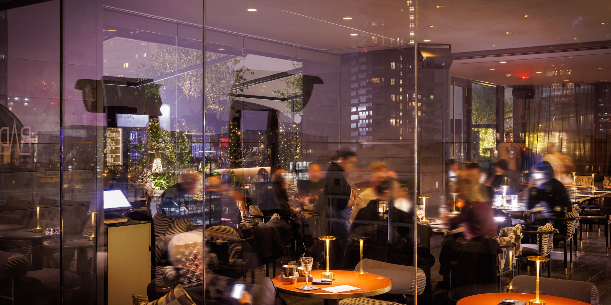 Modern restaurant lounge at night with guests dining and relaxing.