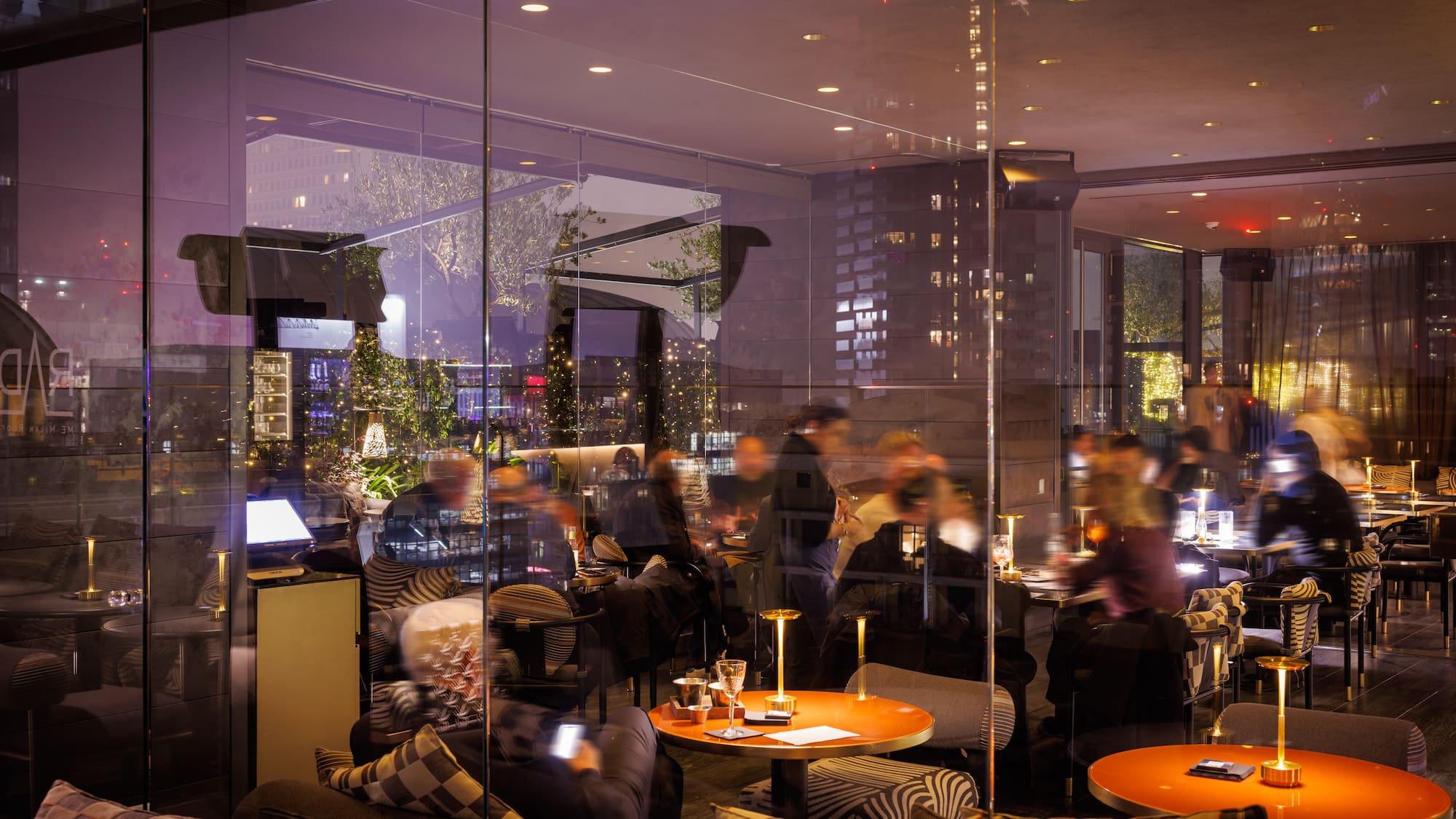Modern restaurant lounge at night with guests dining and relaxing.