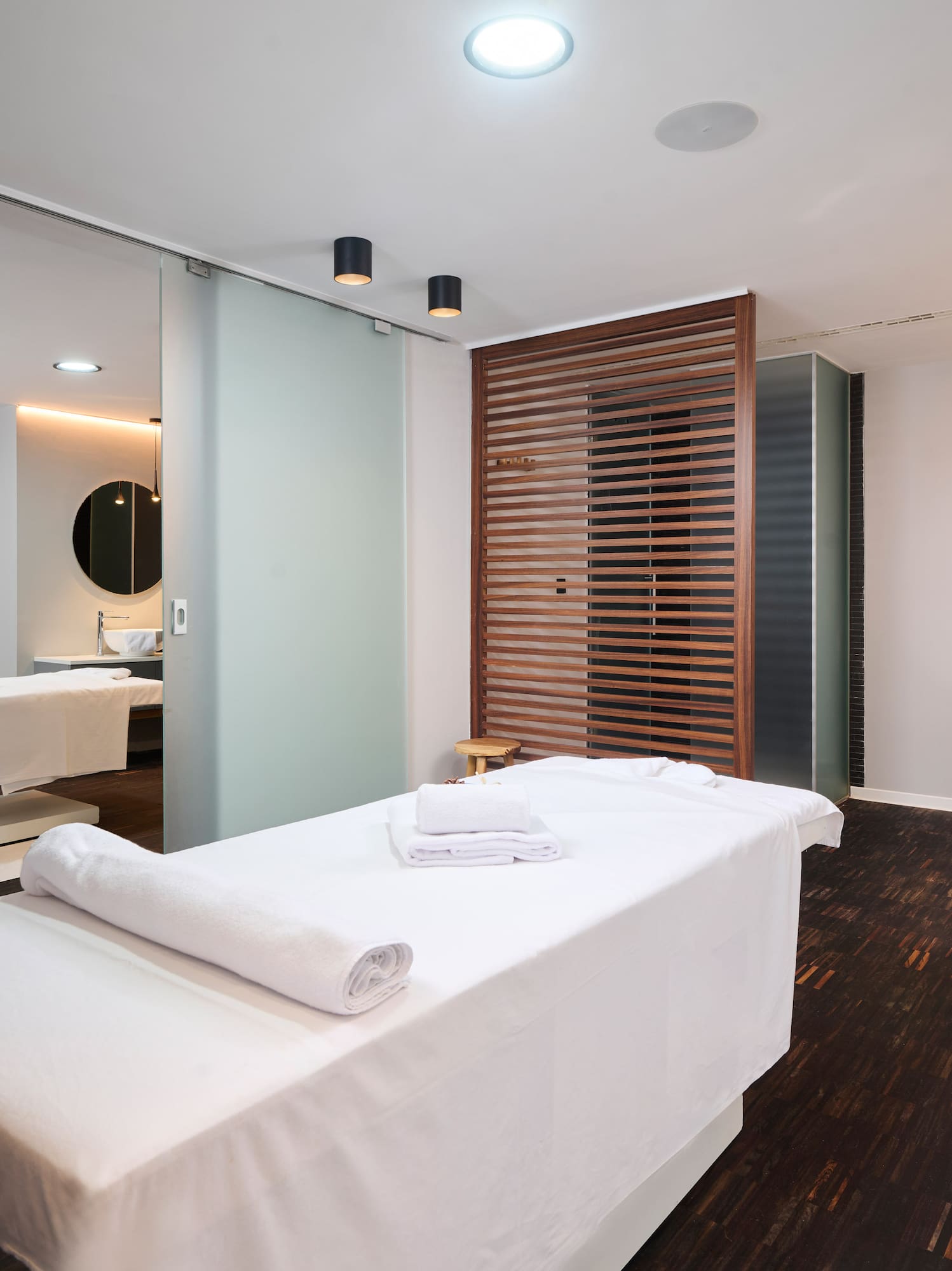 a massage room with white beds and a mirror