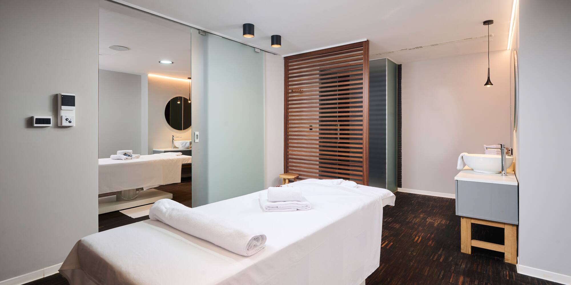 a massage room with white beds and a mirror