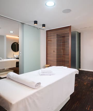 a massage room with white beds and a mirror