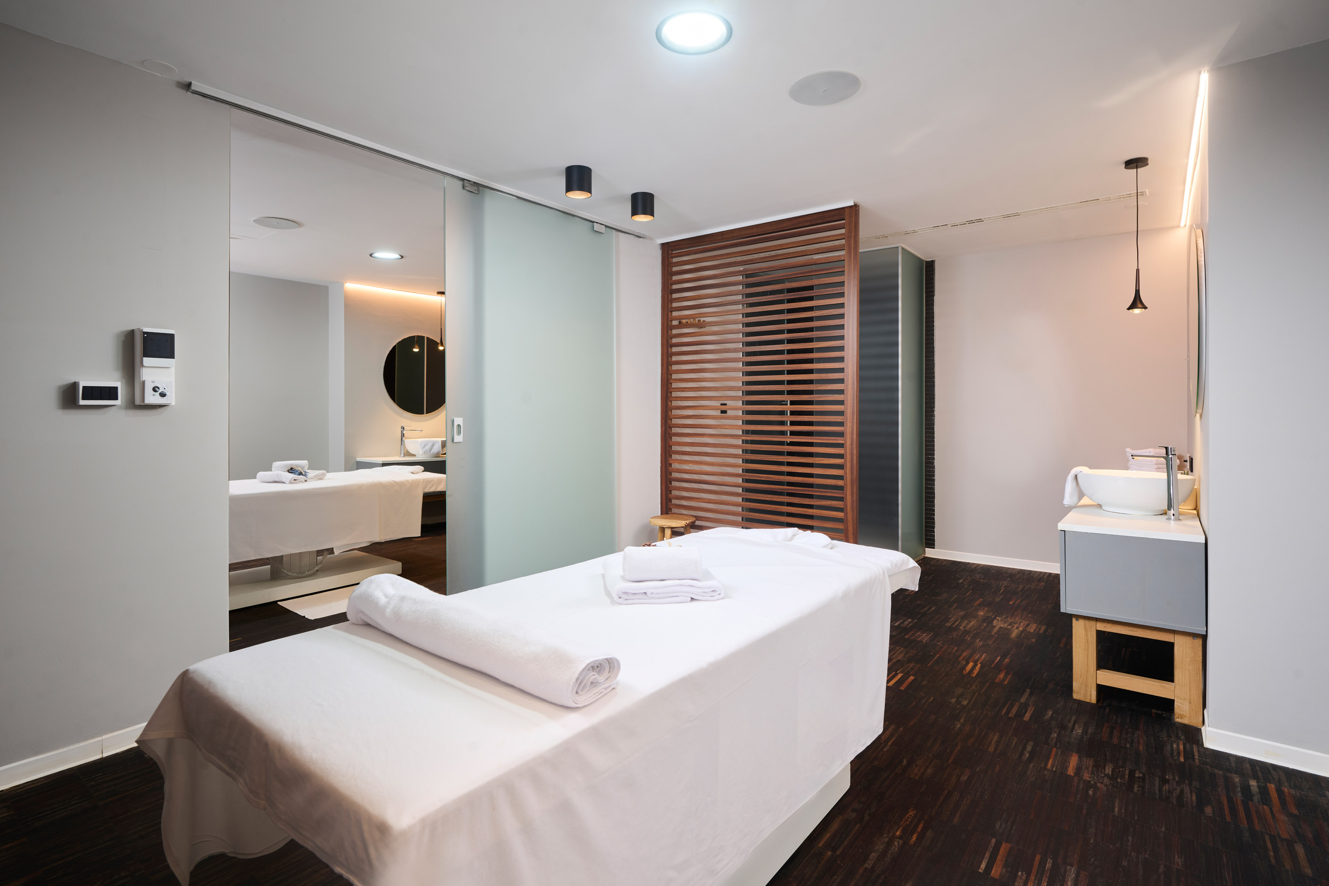 a massage room with white beds and a mirror