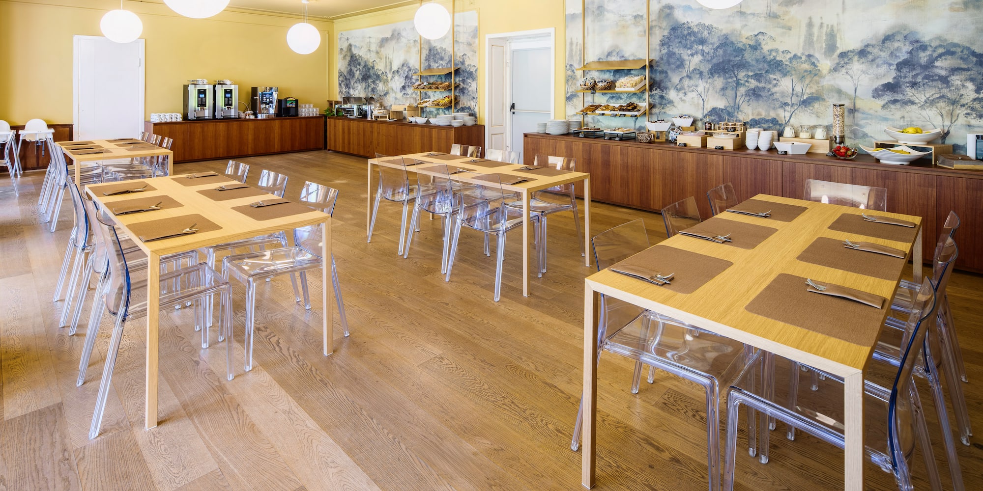 Modern breakfast room with wooden tables, clear chairs, buffet, and nature murals.